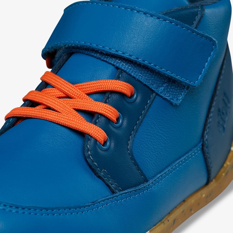 Moderner blauer Schuh mit Klettverschluss und lebhaften orangen Schnürsenkeln, ideal für einen sportlichen Auftritt.