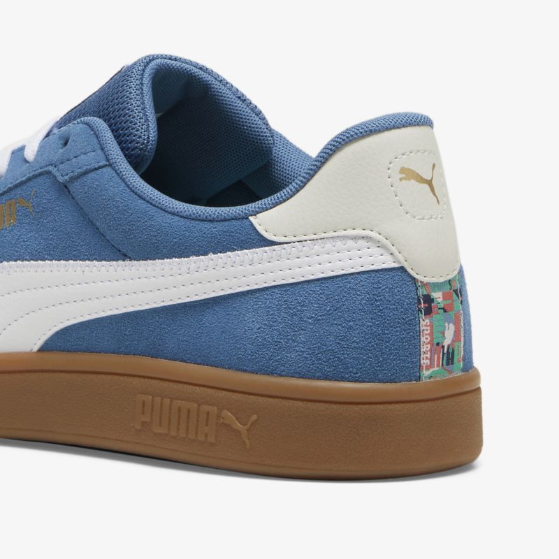 Detailaufnahme eines blauen Wildledersneakers mit weißem Markenlogo und brauner Gummisohle, modisch und bequem