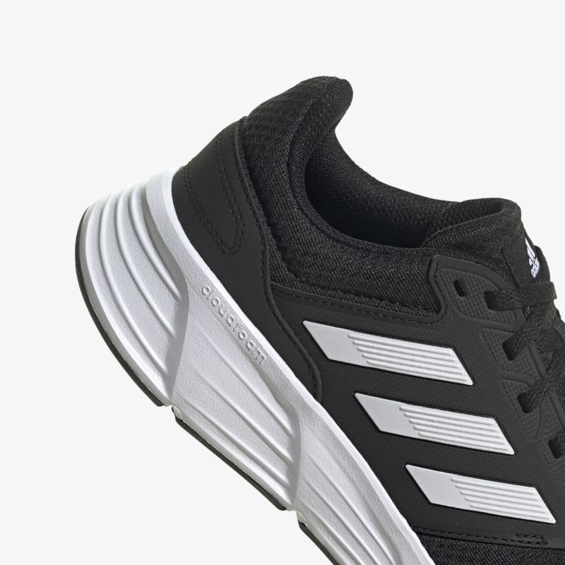 Schwarzer Sportschuh mit markanten weißen Streifen und robuster Sohle für optimalen Komfort und Performance.