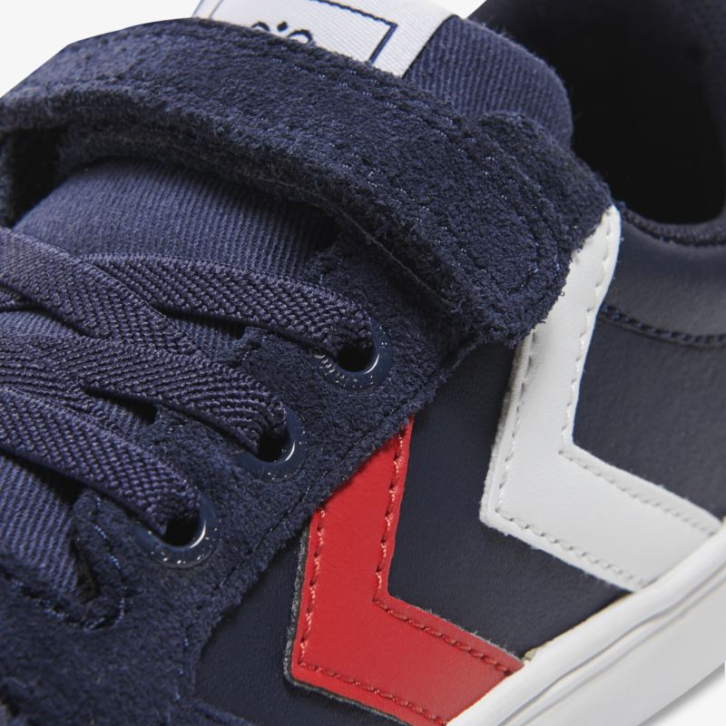 Sportlicher Sneaker mit Klettverschluss und farblich abgesetzten Details in Blau, Rot und Weiß.