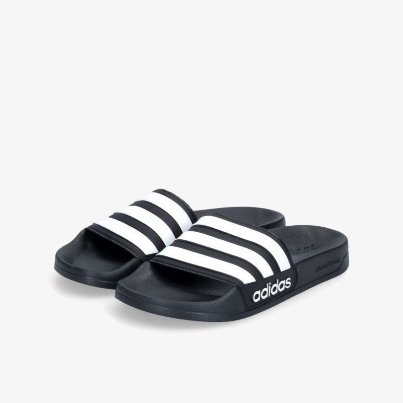 Schwarze Badeschlappen mit ikonischen weißen Streifen und markantem Logo, ideal für Alltag und Freizeit.