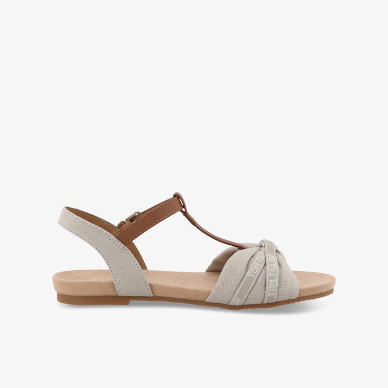 Seitliche Ansicht einer bequemen offenen Sandale mit verstellbarem Riemen und flacher Sohle in Beige