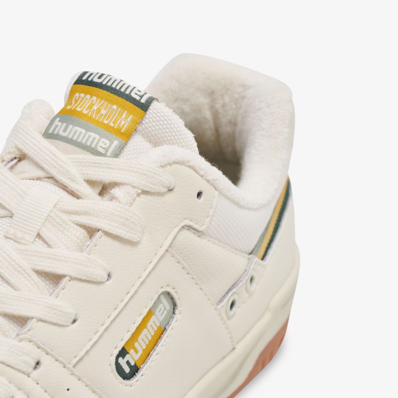 Detailaufnahme eines bequemen Sportschuhs in Beige mit gepolstertem Einstieg und markantem Hummel-Logo
