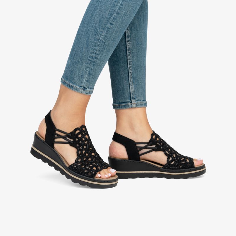 Schwarze, komfortable Sandalen mit Keilabsatz, verstellbaren Riemen und rutschfester Sohle, getragen am Fuß