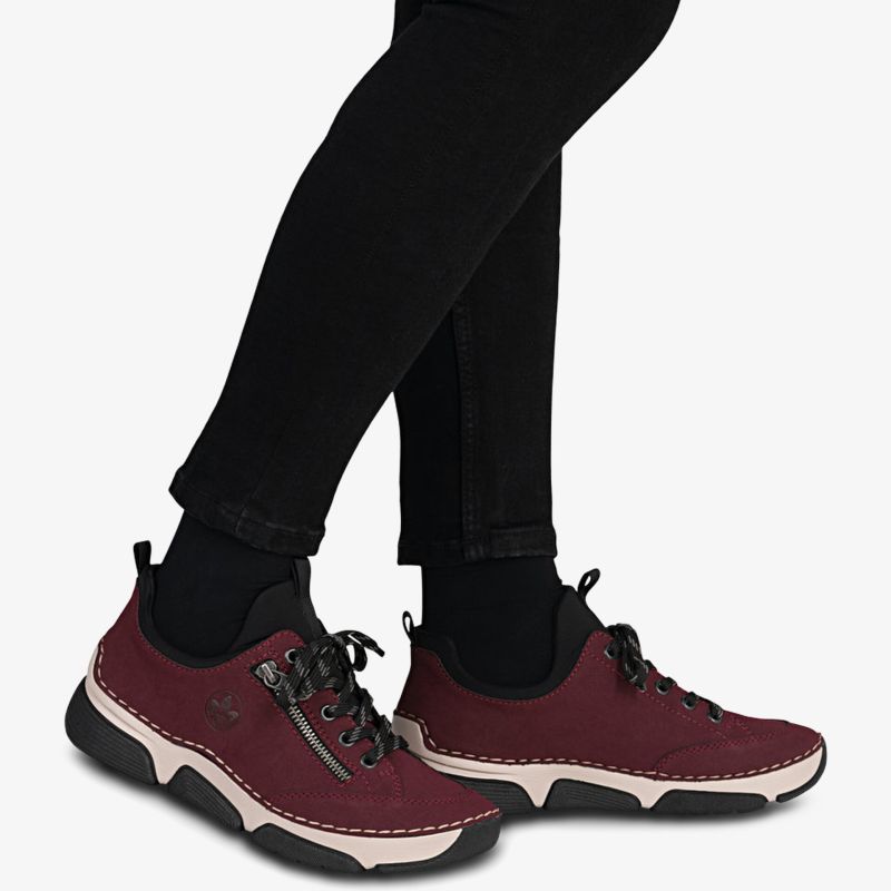 Bequeme und modische sportliche Schuhe mit flexibler Laufsohle und schnürbarem Design in Rot getragen