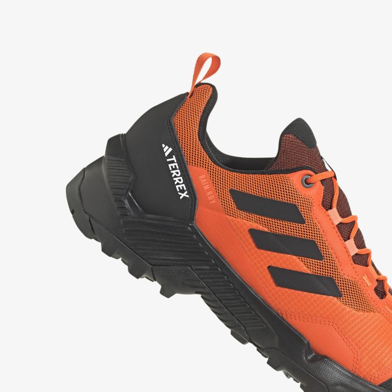 Robuster orangefarbener Sportschuh mit griffiger Sohle und seitlichem Logo für Outdoor-Abenteuer.