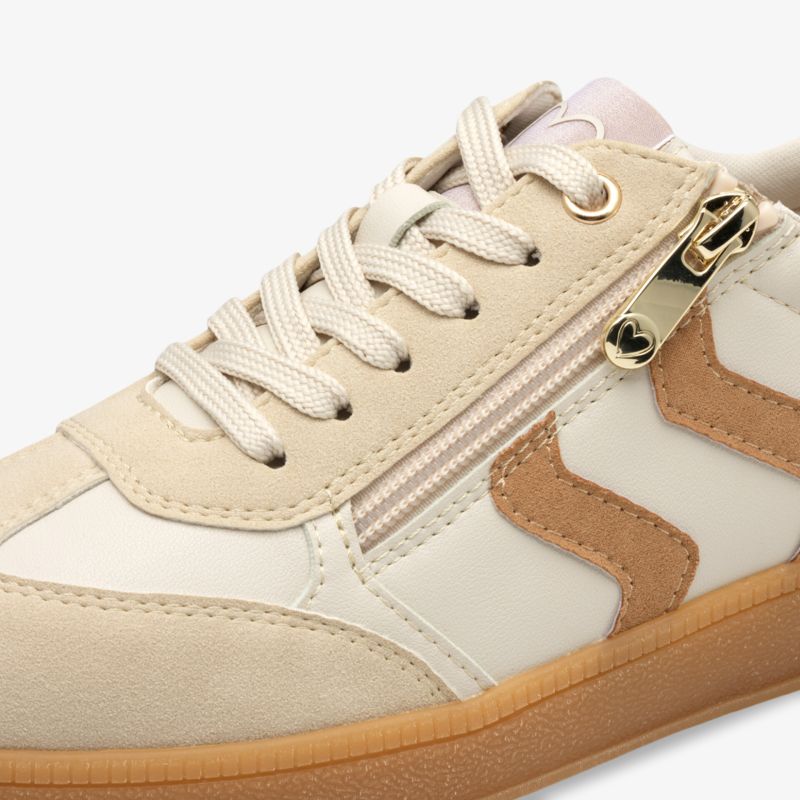 Nahaufnahme beiger Sneaker mit Schnürung und funktionalem Reißverschluss seitlich am Schuh