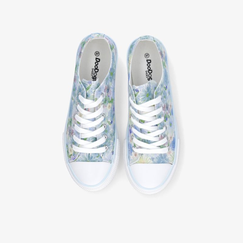 Bequeme blaue weiße Sneaker mit floralem Muster und stabilen Schnürsenkeln als Paar von oben