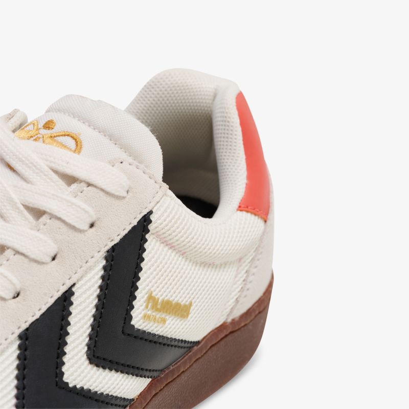 Detailaufnahme eines Sportschuhs mit hochwertigem Material, gepolstertem Kragen und auffälligem Logo in Weiß, Schwarz und Rot