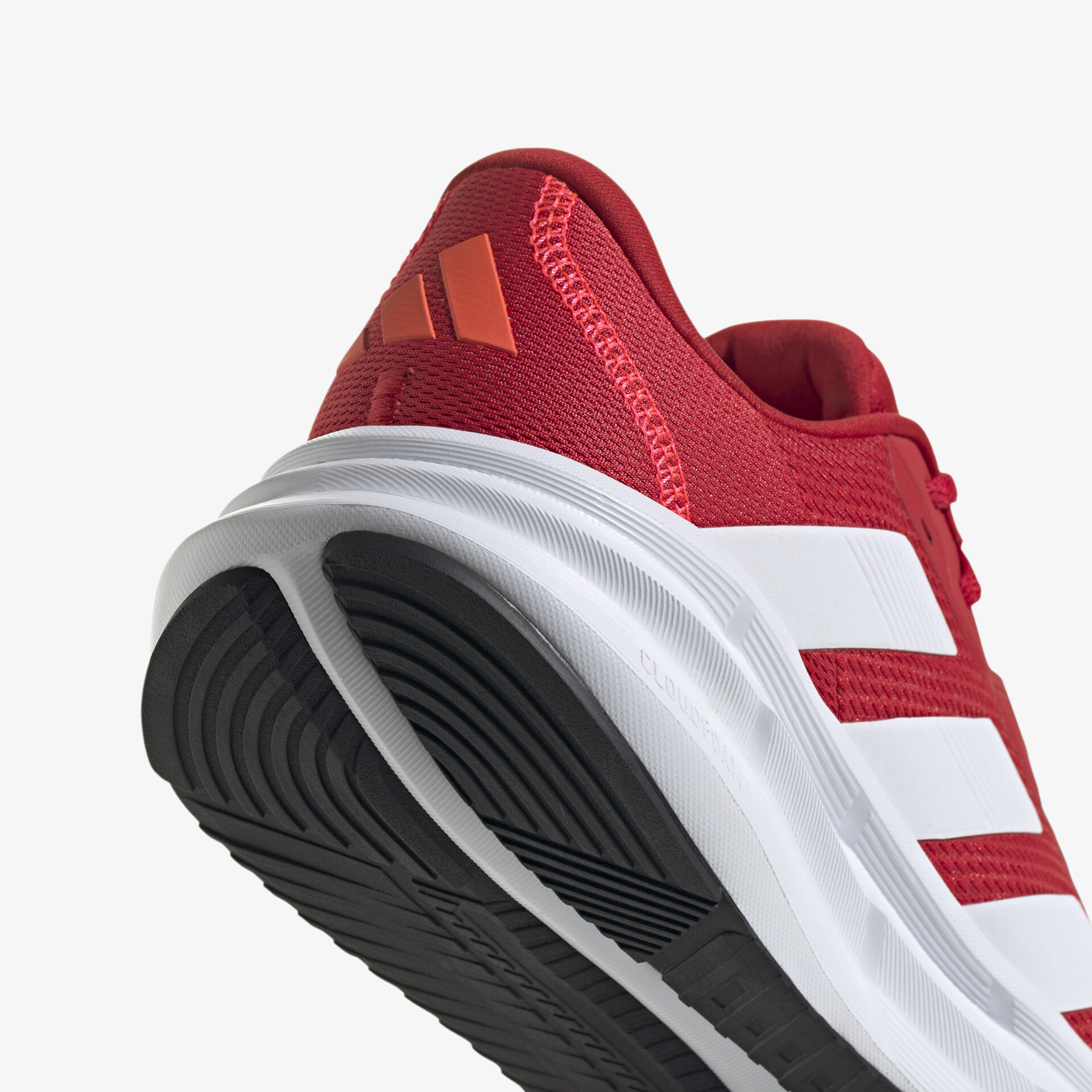 Detailaufnahme eines roten Sportschuhs mit weißem Streifen und profilierter, rutschfester Sohle