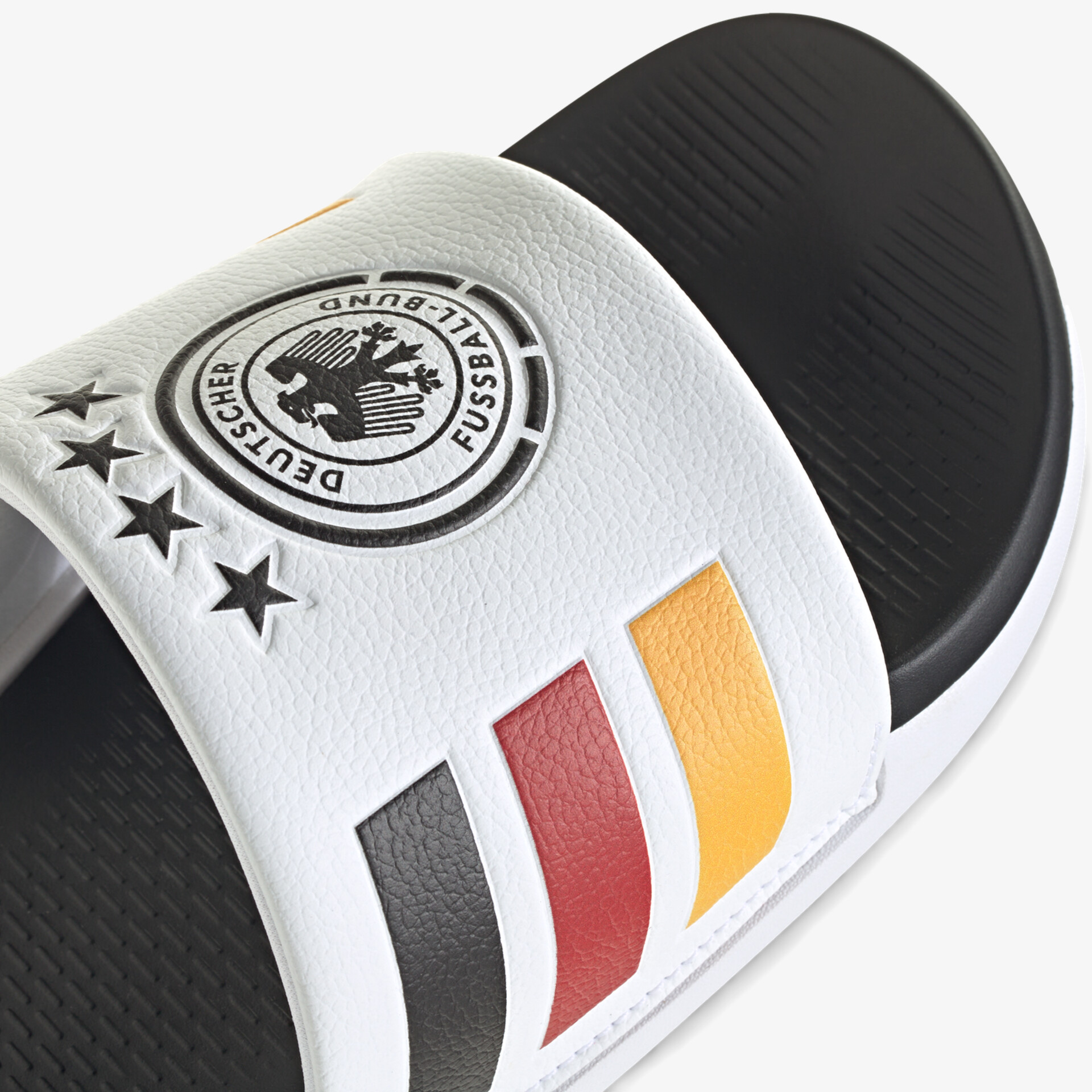 Nahaufnahme eines sportlichen weißen und schwarzen Slippers mit mehrfarbigen Streifen und Logo