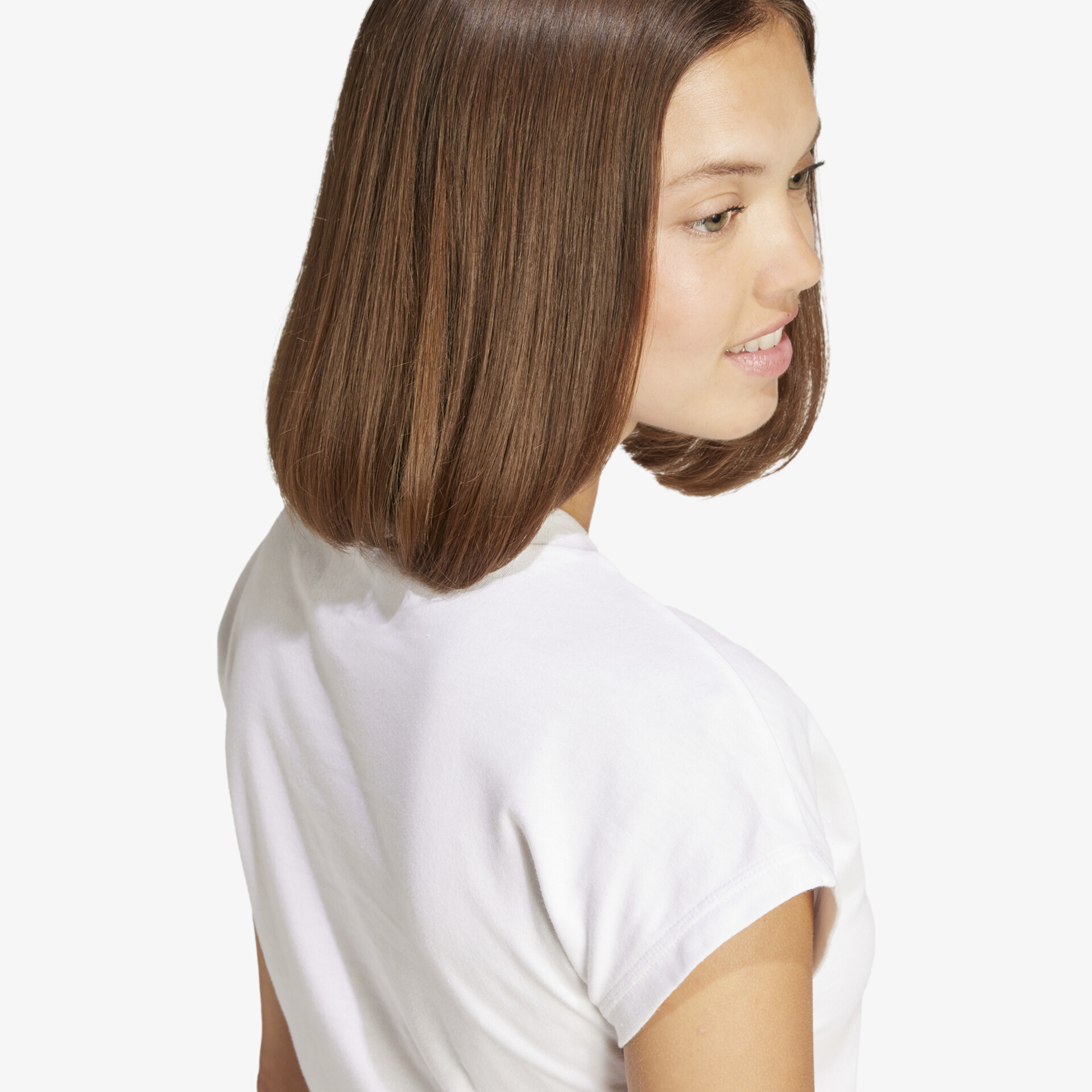 Frau mit glatten, braunen, mittellangen Haaren trägt weißes T-Shirt, Blick von schräg hinten