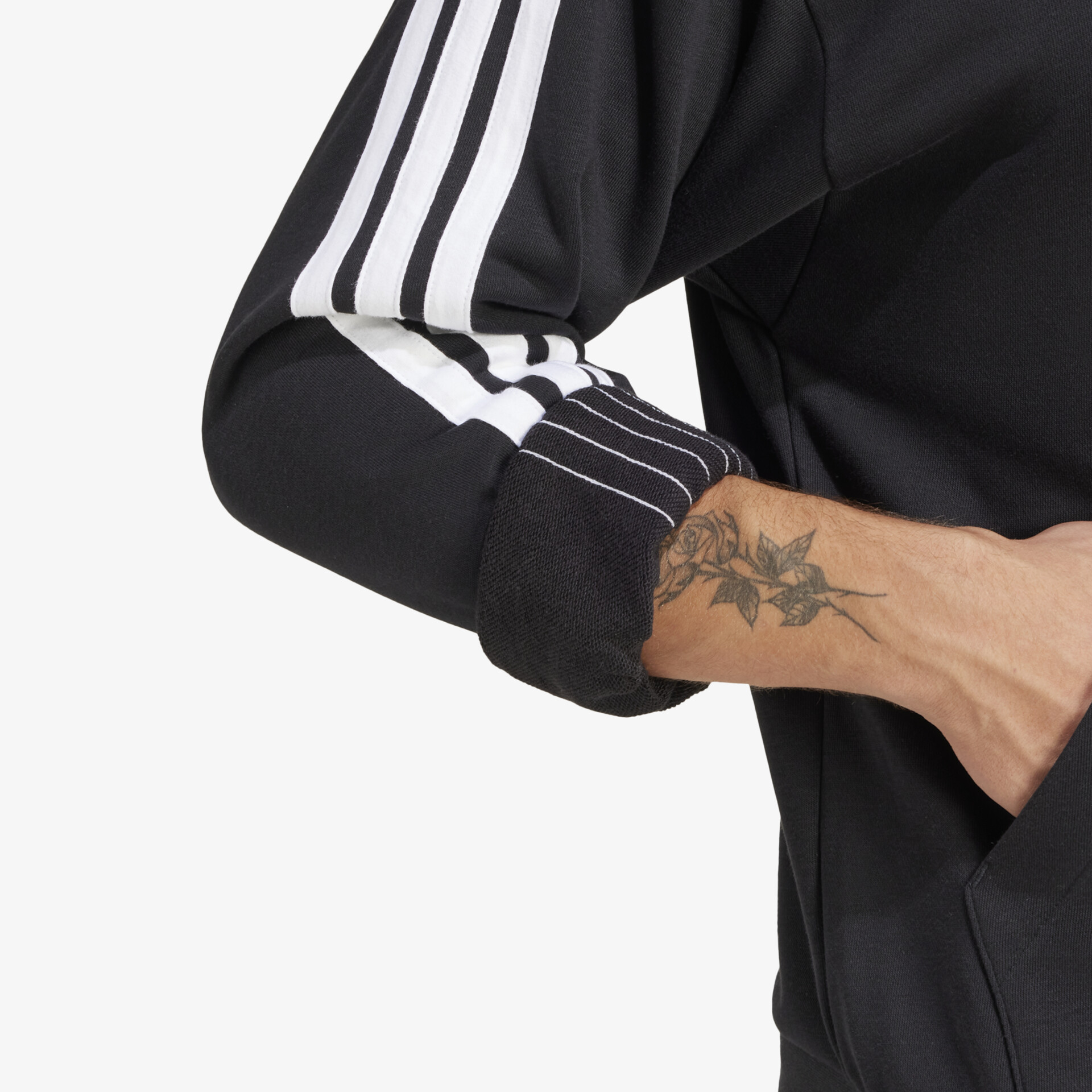 Herangezoomter Ausschnitt eines schwarzen sportlichen Shirts mit weißem Streifen und sichtbarem Tattoo am Arm