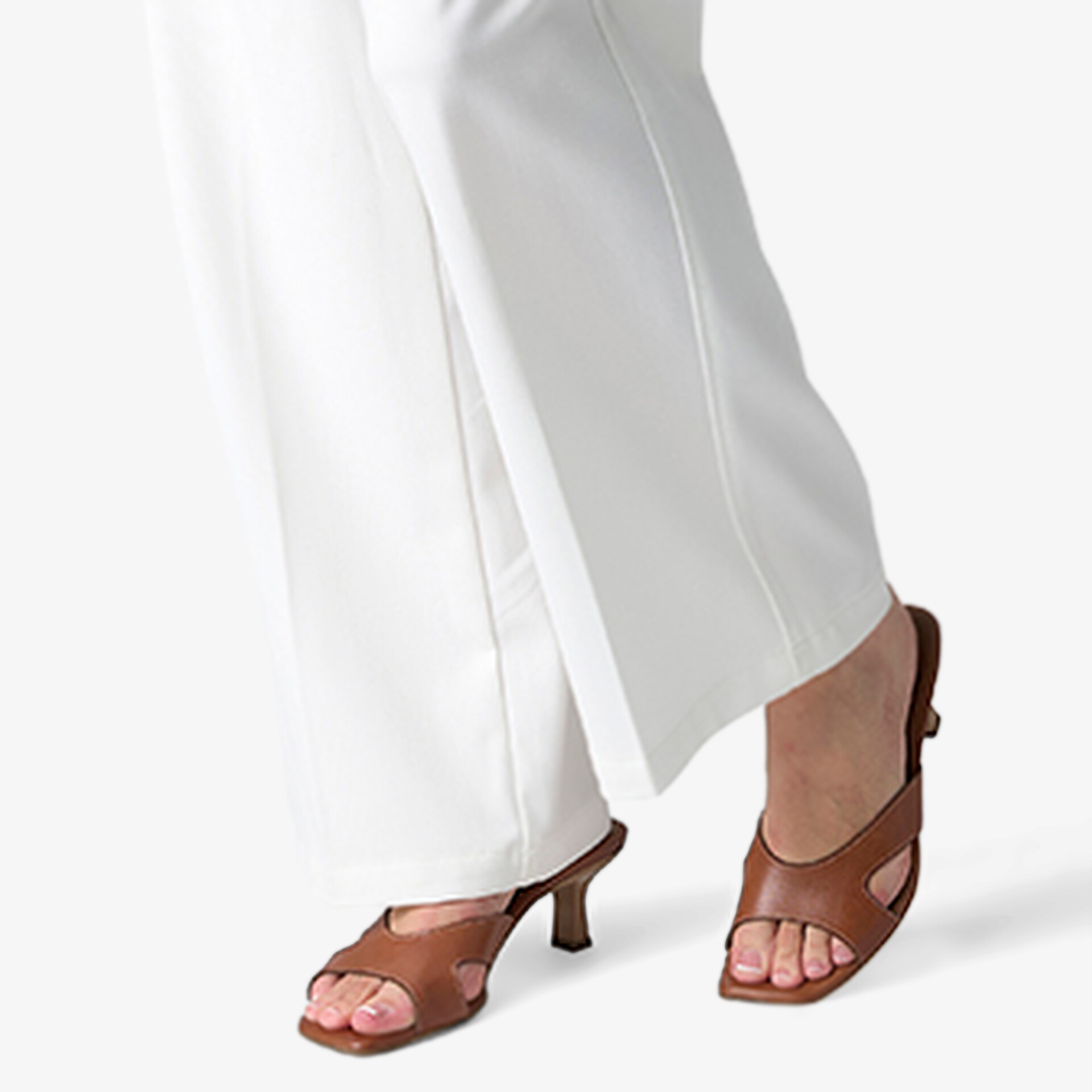 Braune Sandaletten aus hochwertigem Leder mit Absatz, elegant und stilvoll zu weißen Hosen getragen.