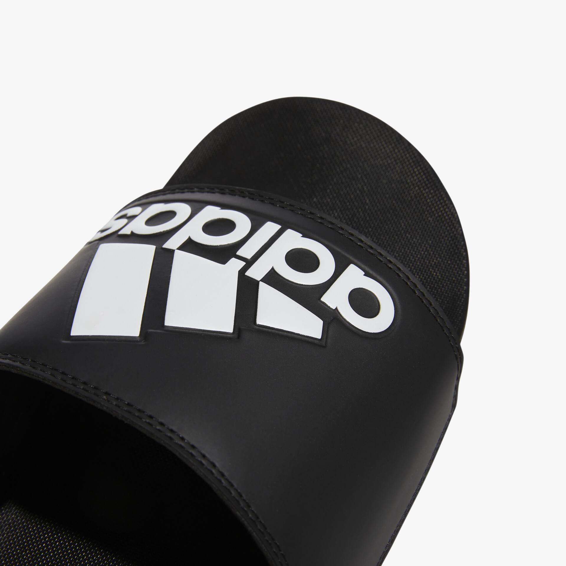 Detailaufnahme eines schwarzen Adidas Slides mit weißem Logo und weichem Riemen für bequemen Sitz