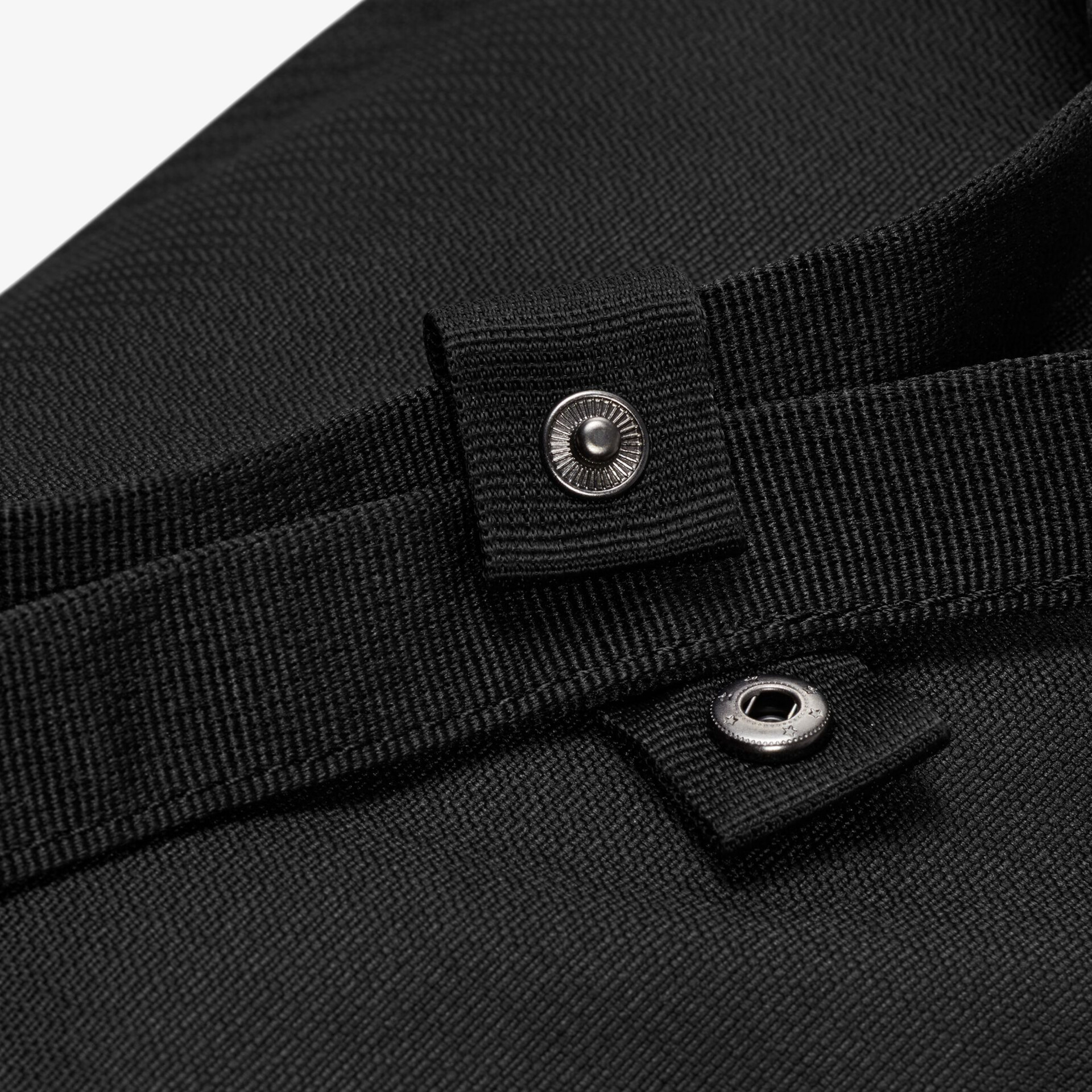 Schwarzes Stoffdetail mit Schnalle und Knopf für sicheren Verschluss