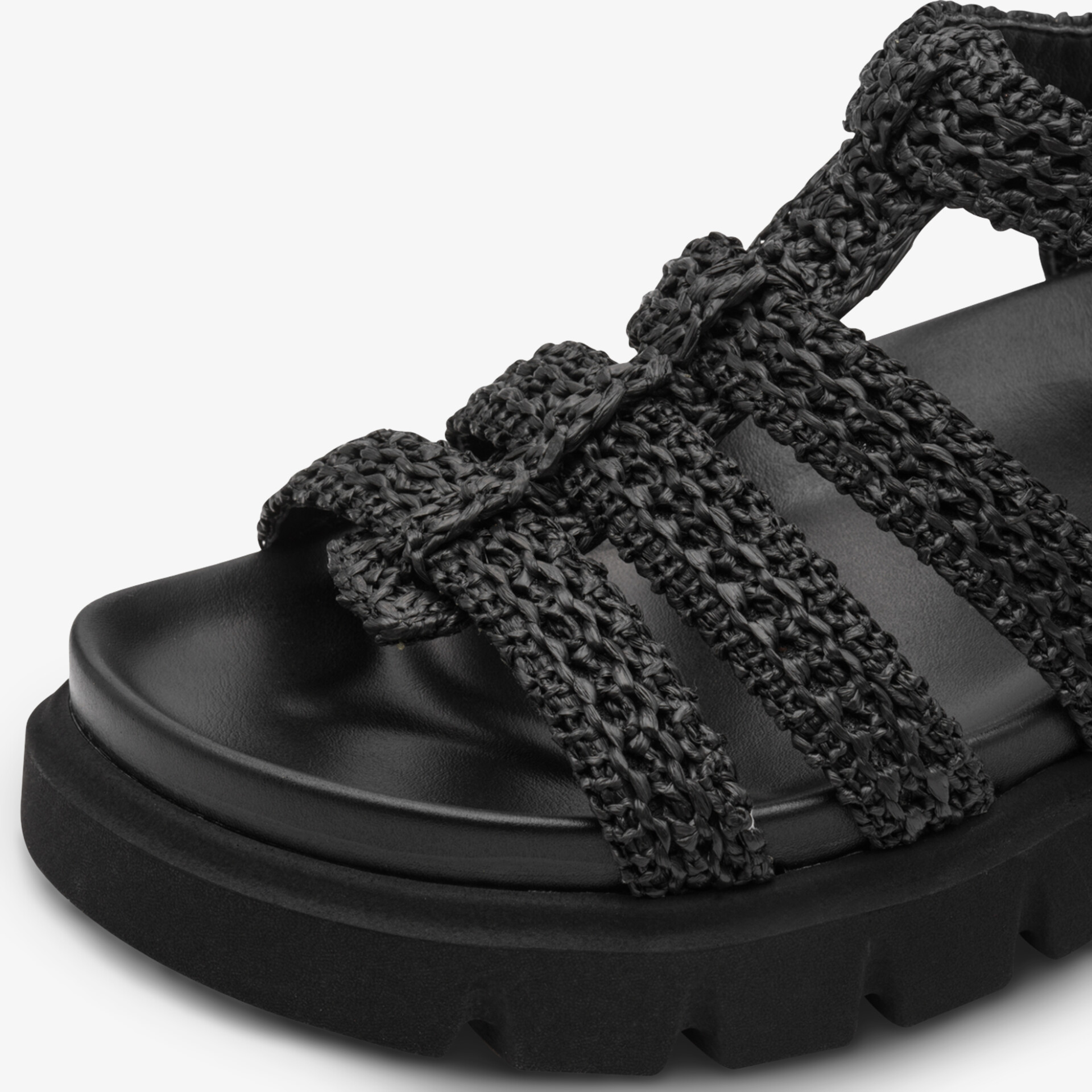 Schwarze Sandale mit geflochtenem Riemen und robuster Sohle aus seitlicher Perspektive