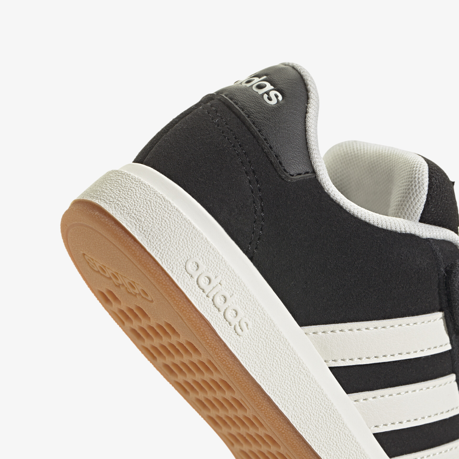 Detailaufnahme eines schwarzen Adidas Sneakers mit weißen Streifen und robuster brauner Gummisohle