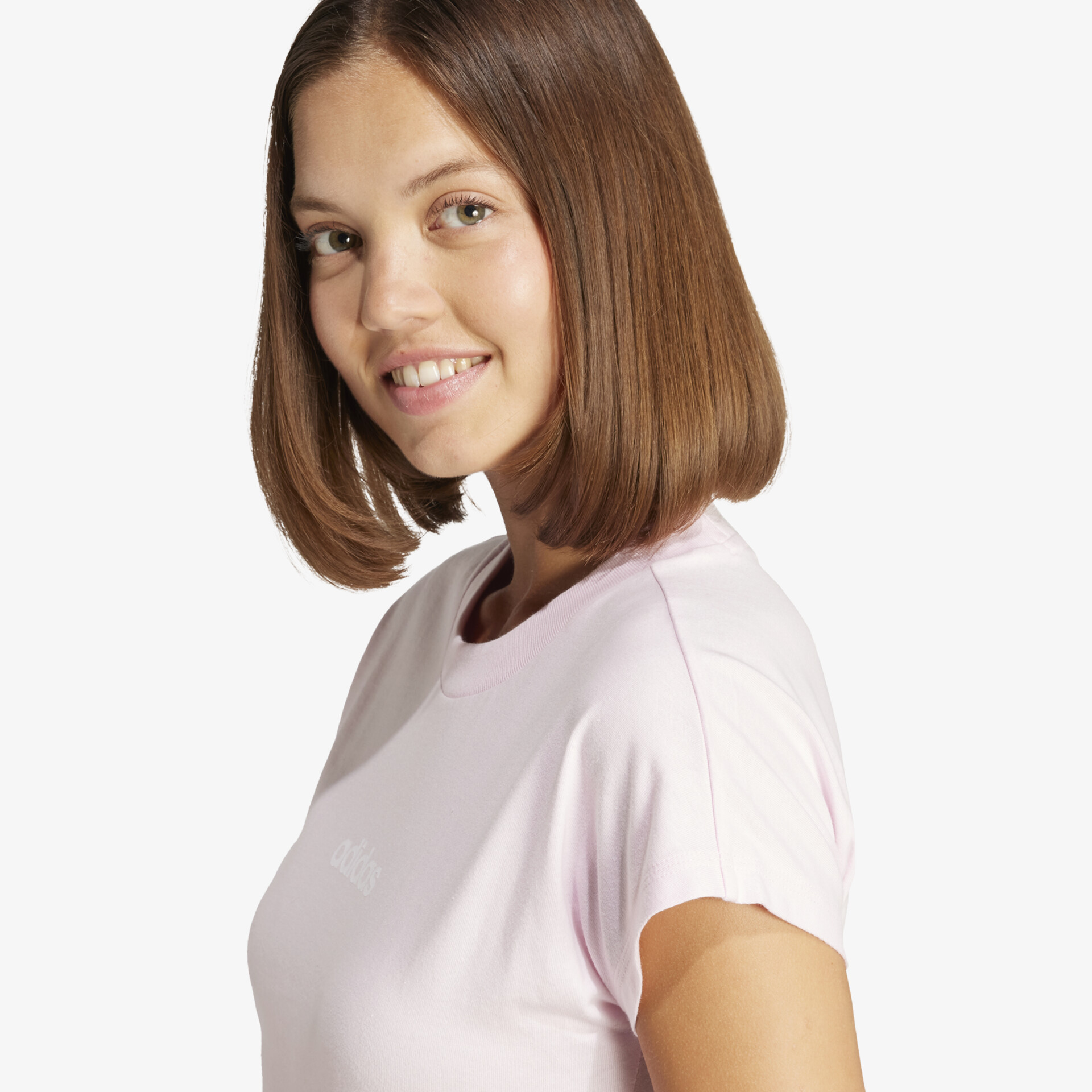 Junge Person mit gesundem Haar und freundlichem Lächeln trägt bequemes rosa T-Shirt in natürlicher Pose