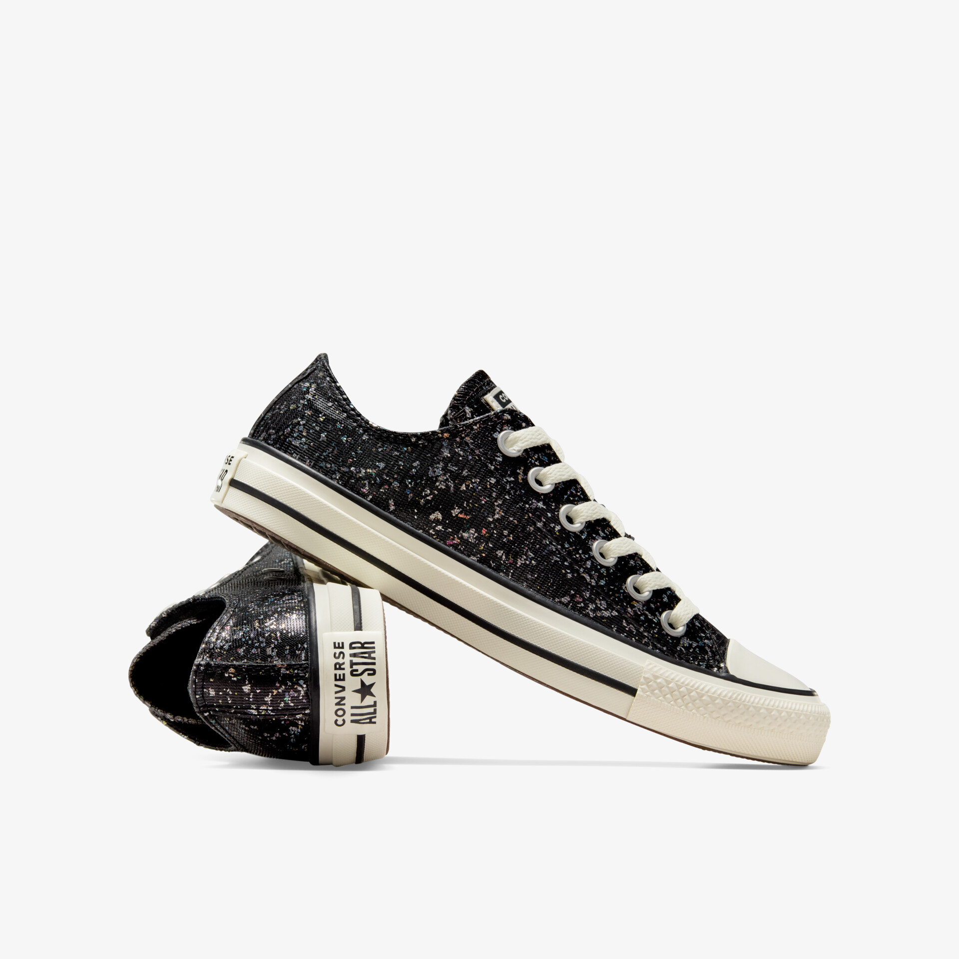 Modischer schwarzer Sneaker mit glitzerndem Material, weißen Schnürsenkeln und cremefarbener Sohle, seitliche Ansicht