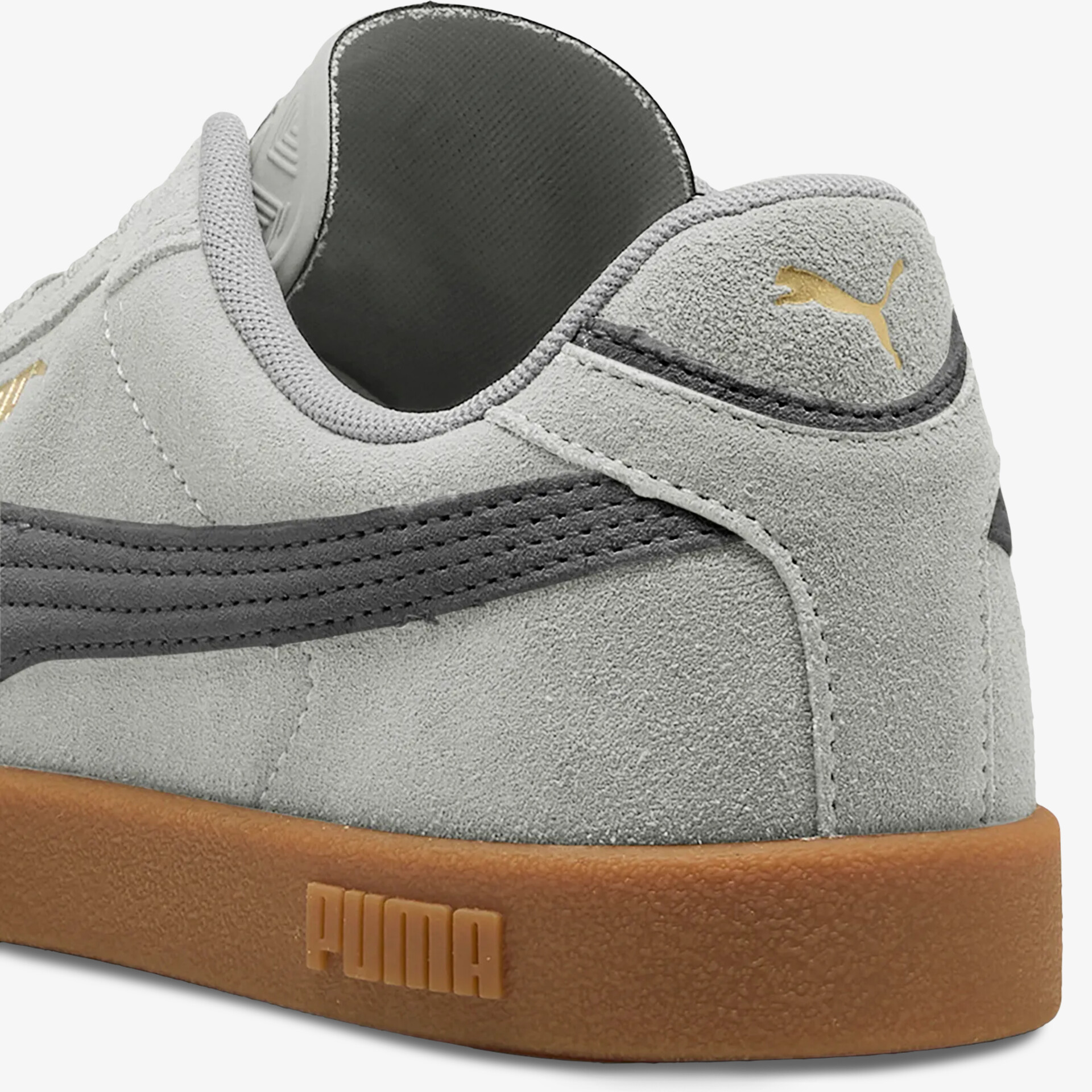 Detailansicht eines grauen Puma Sneakers aus Wildleder mit brauner Gummisohle und Logo am Absatz