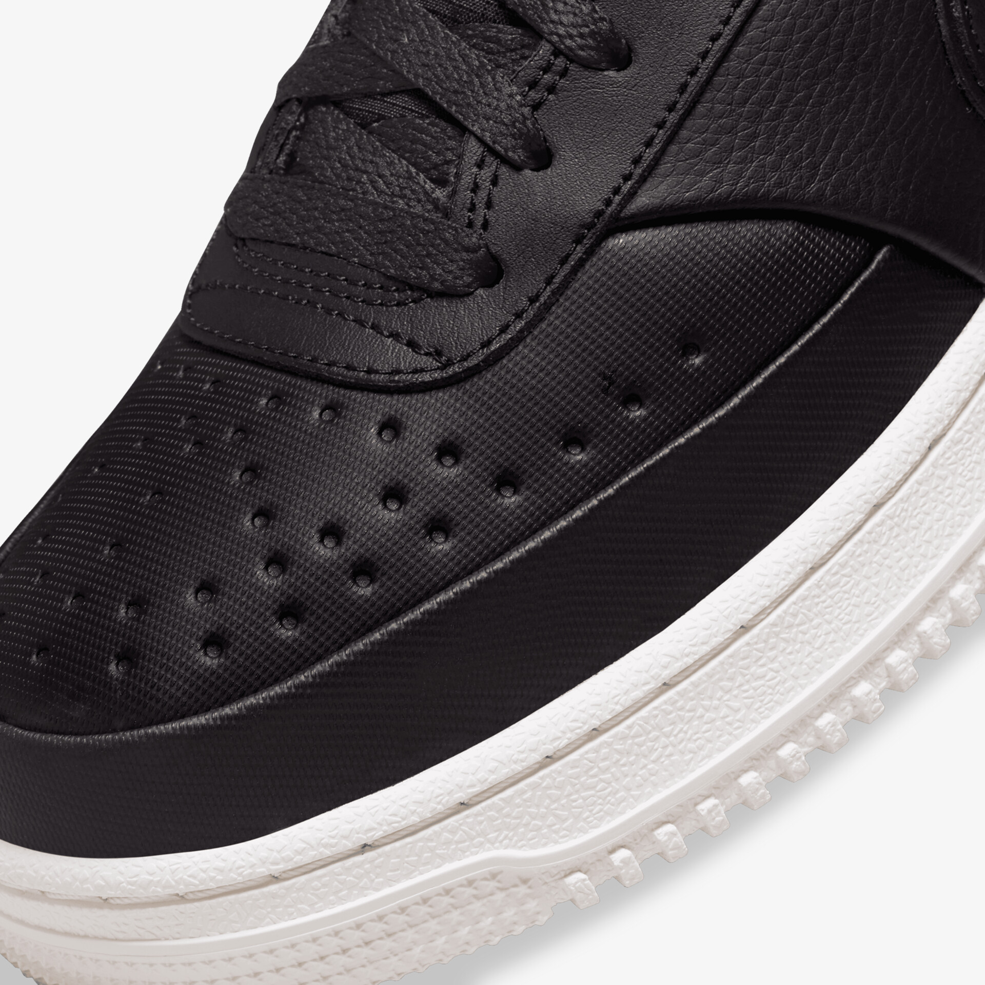 Detailaufnahme eines schwarzen Sneakers mit perforiertem Obermaterial und robuster weißer Sohle