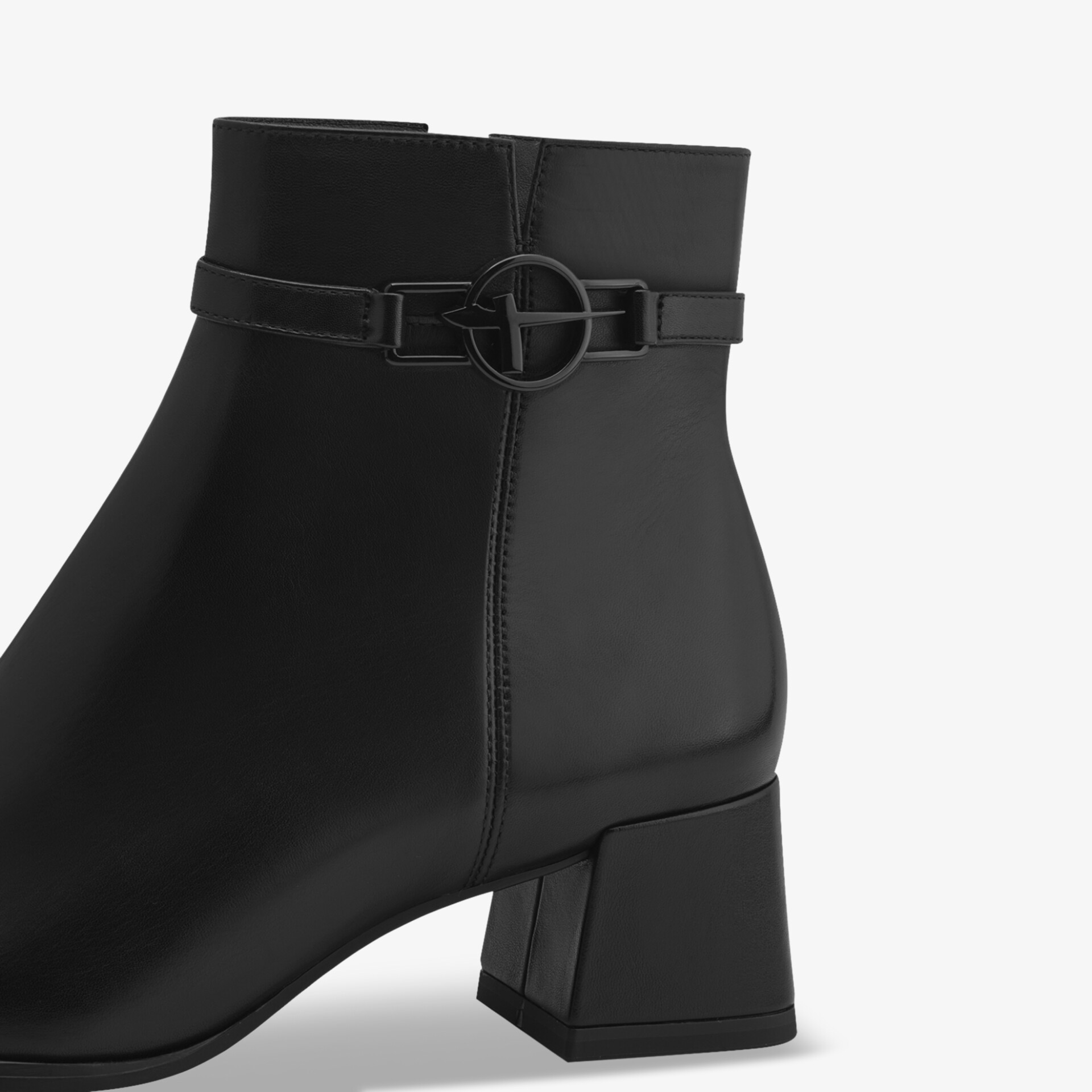 Detailaufnahme eines grauen Stiefels mit niedrigem Blockabsatz und modischem Riemen mit rundem Verschluss