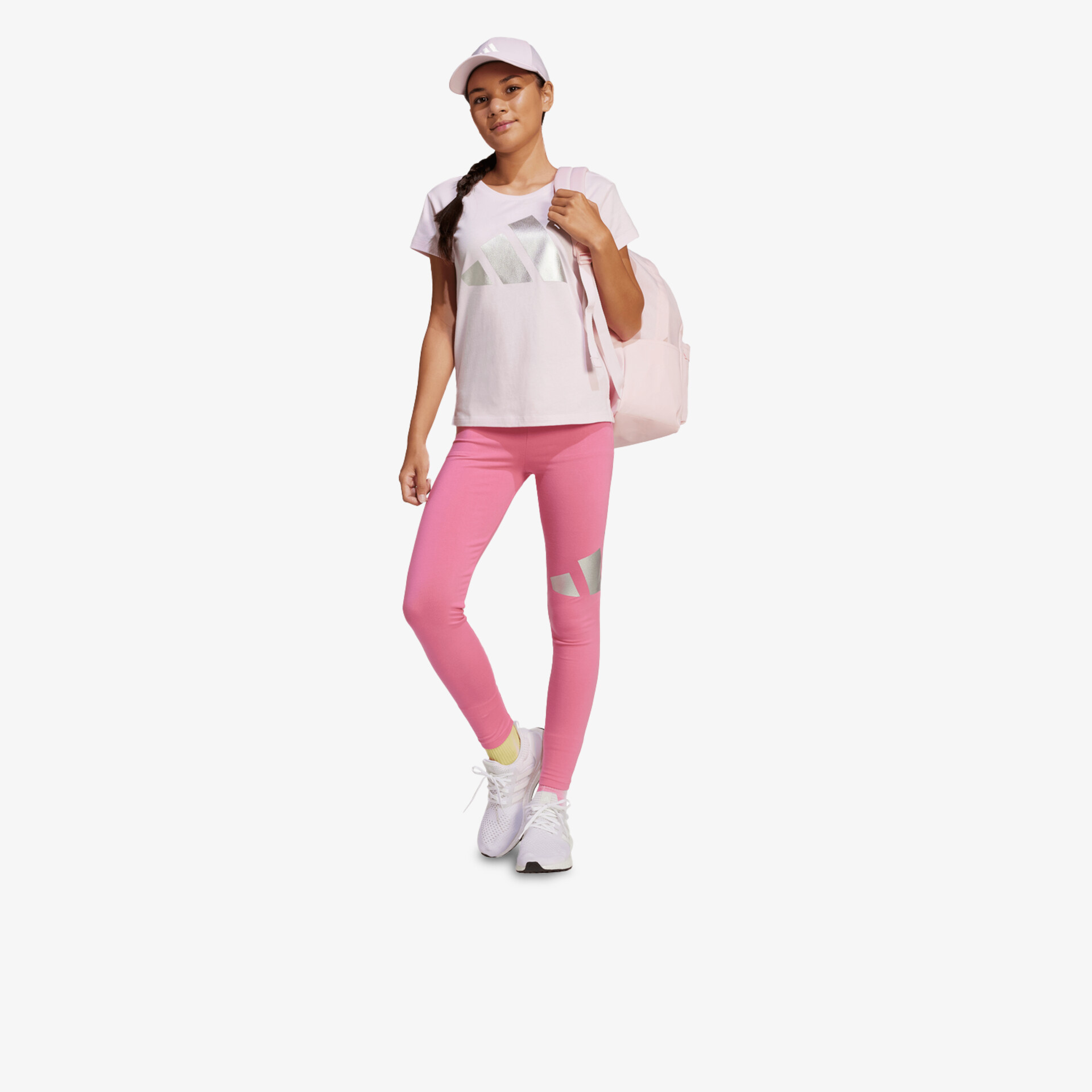 Modell trägt pinke Leggings mit weißem Shirt und Sneakern, sportlich und komfortabel