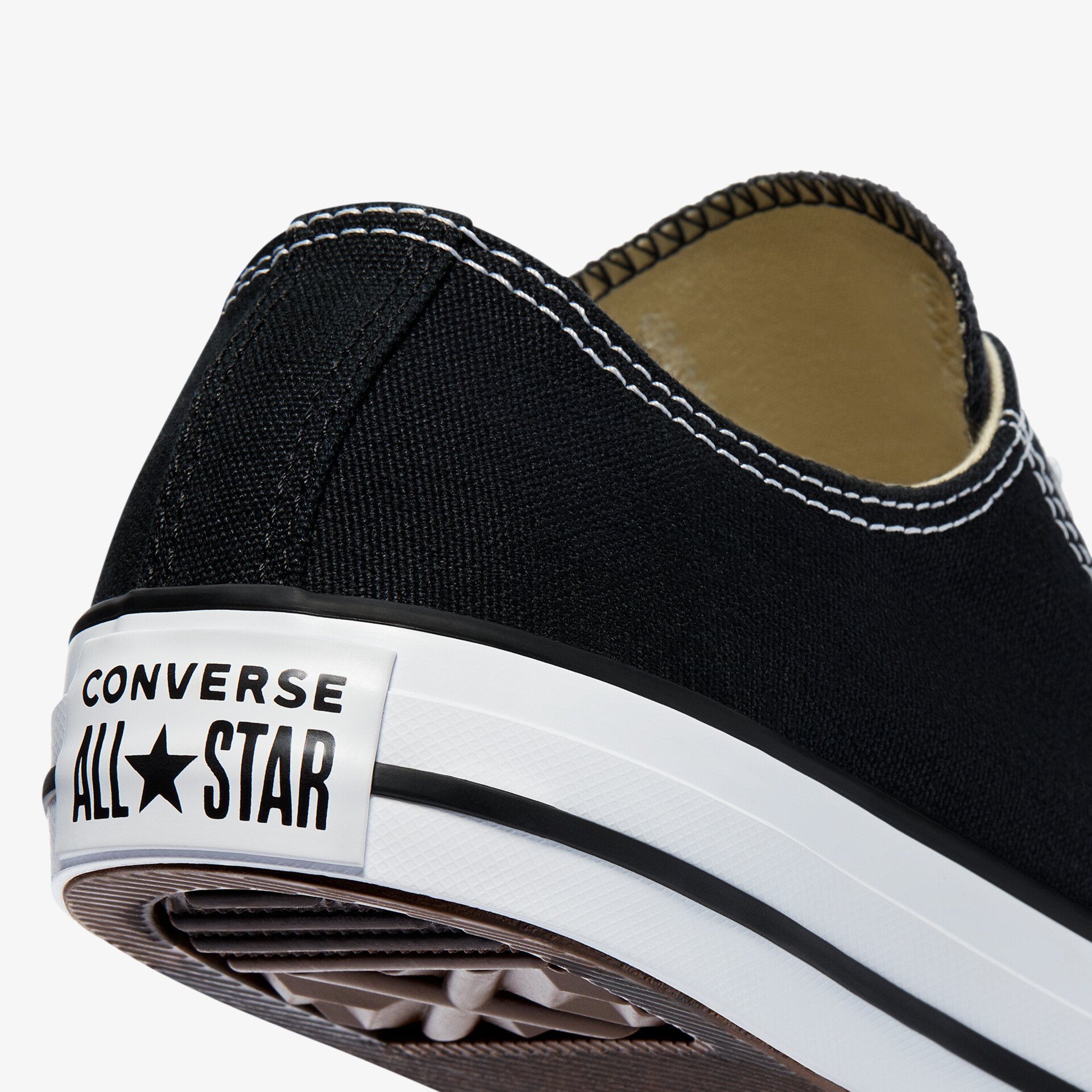 Detailaufnahme der Rückseite eines schwarzen Converse Sneakers mit weißer Gummisohle und Markenlogo