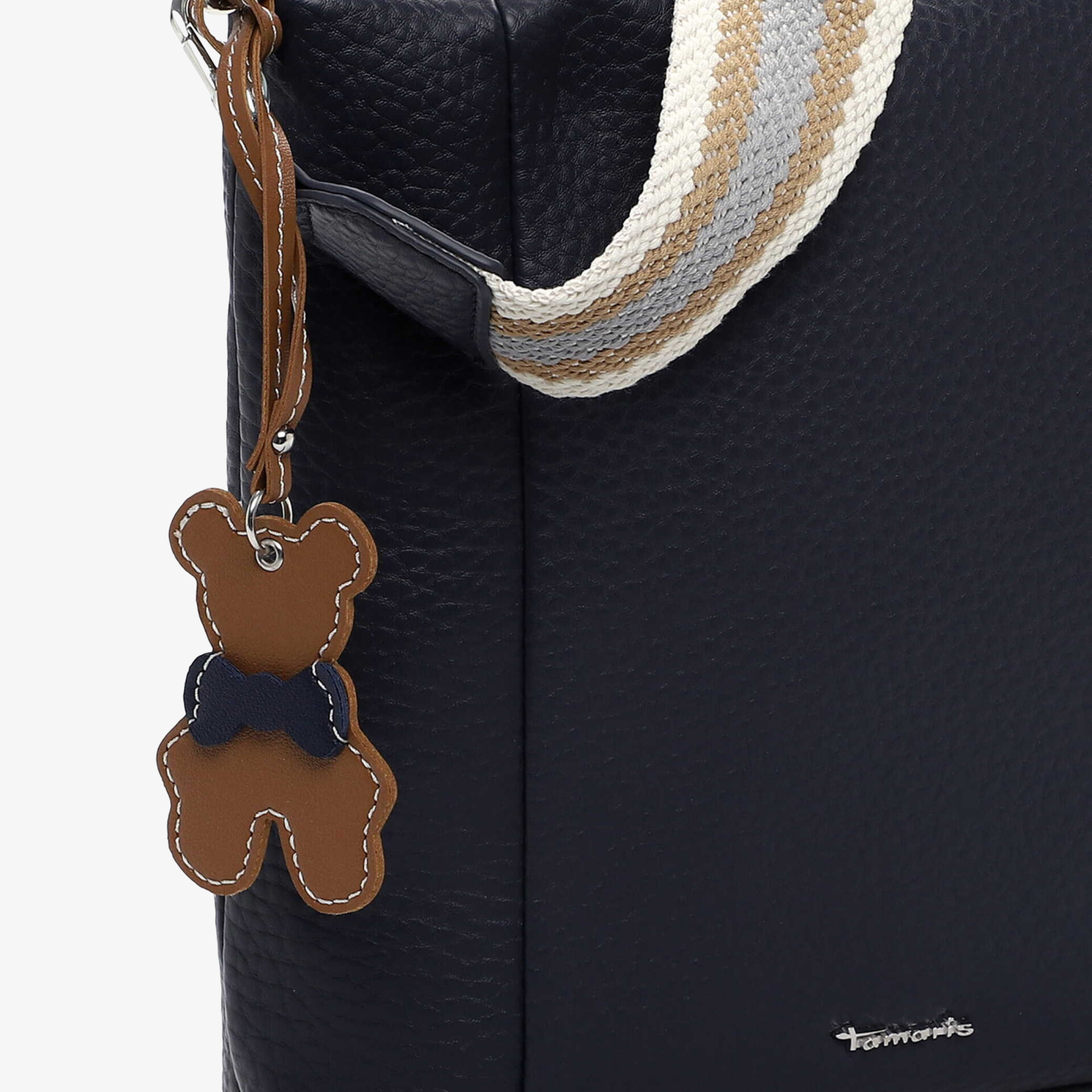 Navy blue bag with textured surface and decorative teddy charm hanging on side, adjustable strap visible