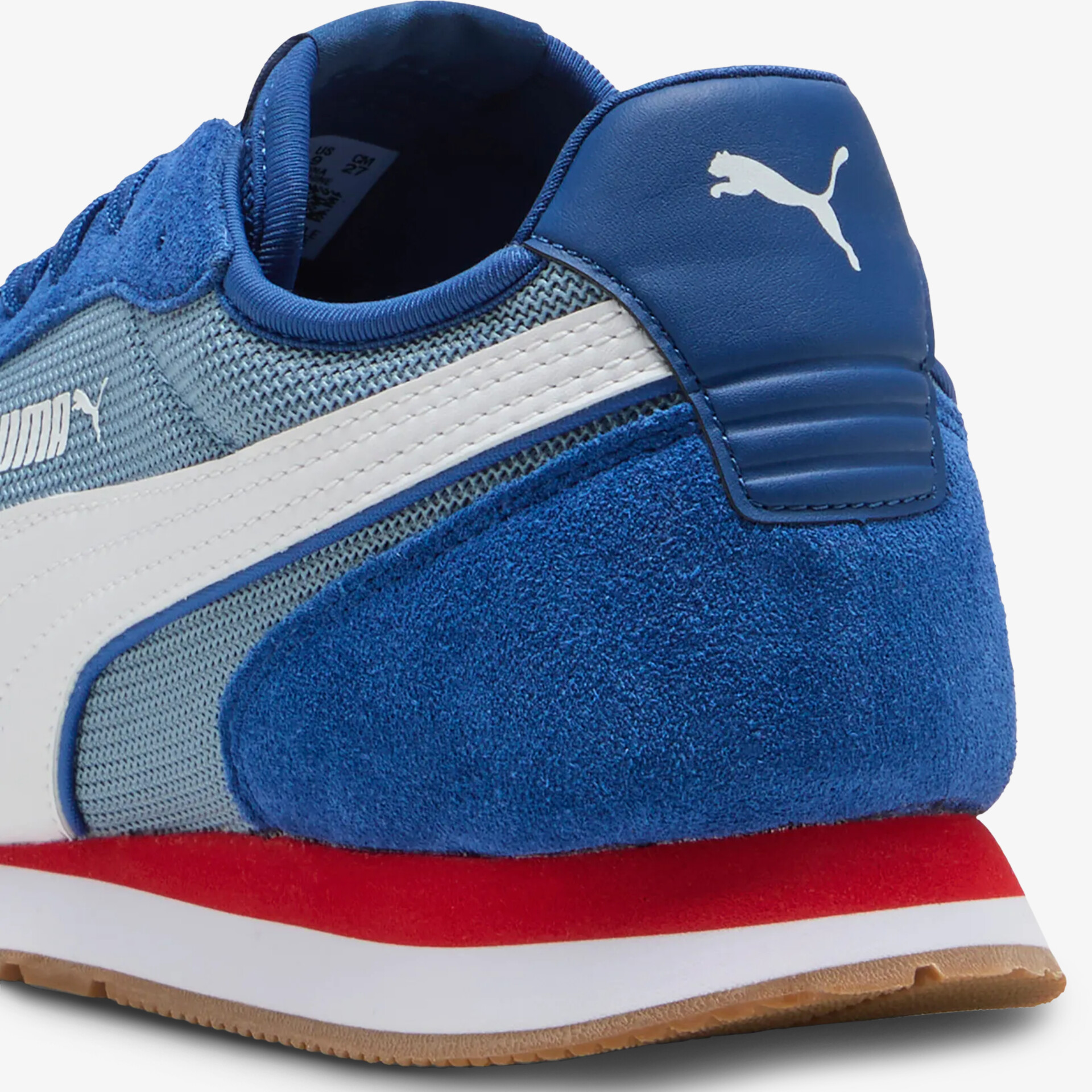 Seitliche Nahaufnahme eines blauen Puma Sneakers mit Wildleder und Mesh, roter Sohle und weißem Logo