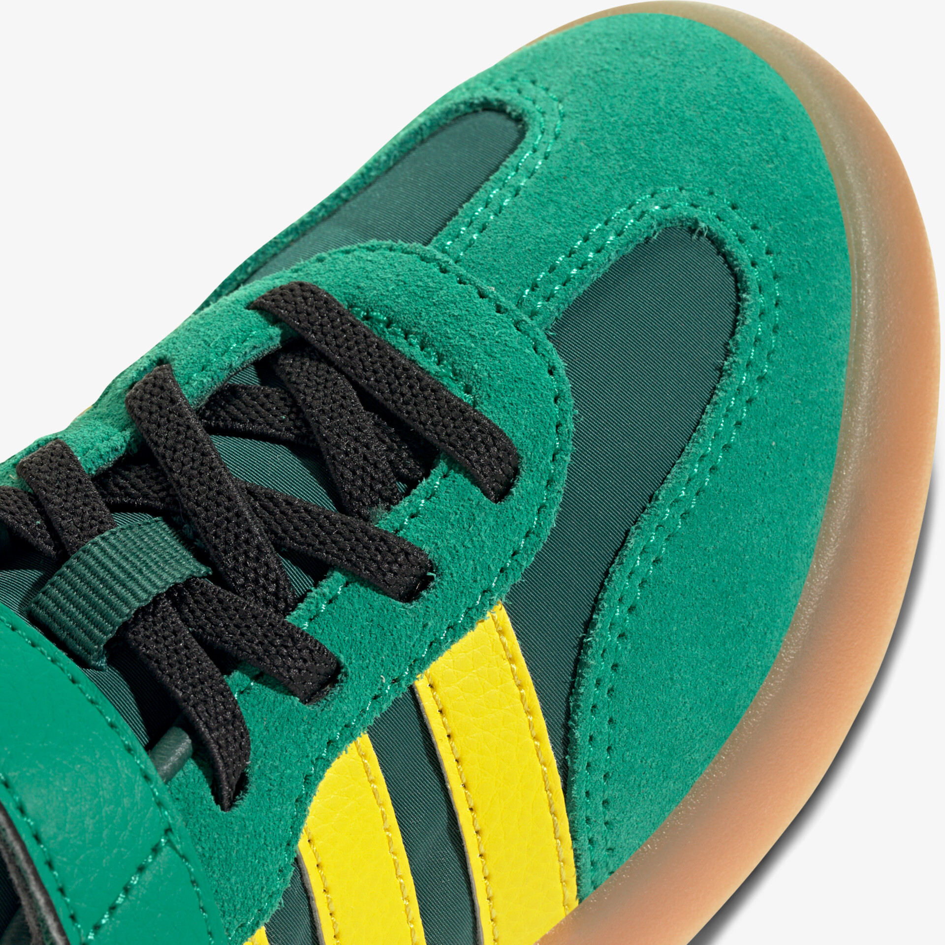 Detailaufnahme eines grünen Sportschuhs mit gelben Streifen und schwarzer Schnürung, rutschfeste Gummisohle sichtbar