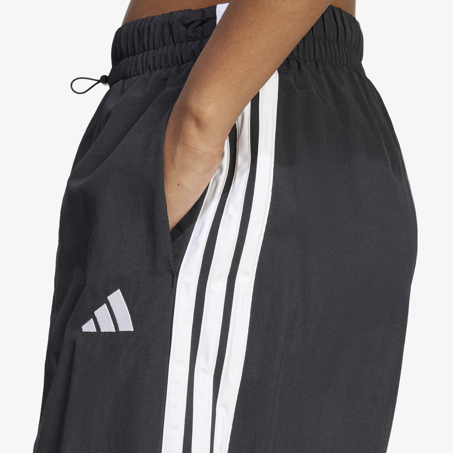 Detailaufnahme von sportlicher Hose mit elastischem Bund, seitlichen Taschen und markantem dreistreifen Design