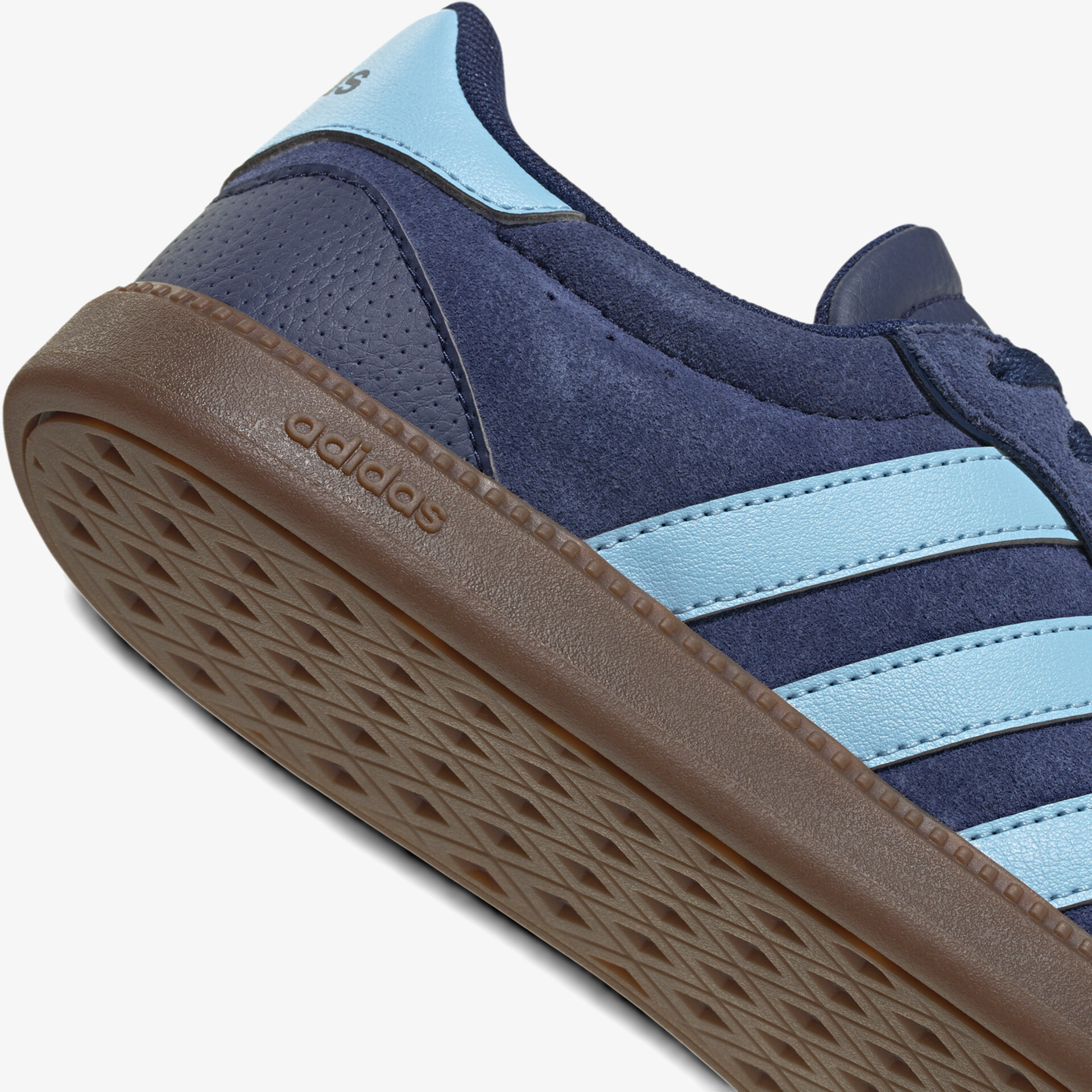 Detailaufnahme eines Adidas Sneakers mit Wildledermaterial und blaue Streifen, robuste braune Gummisohle