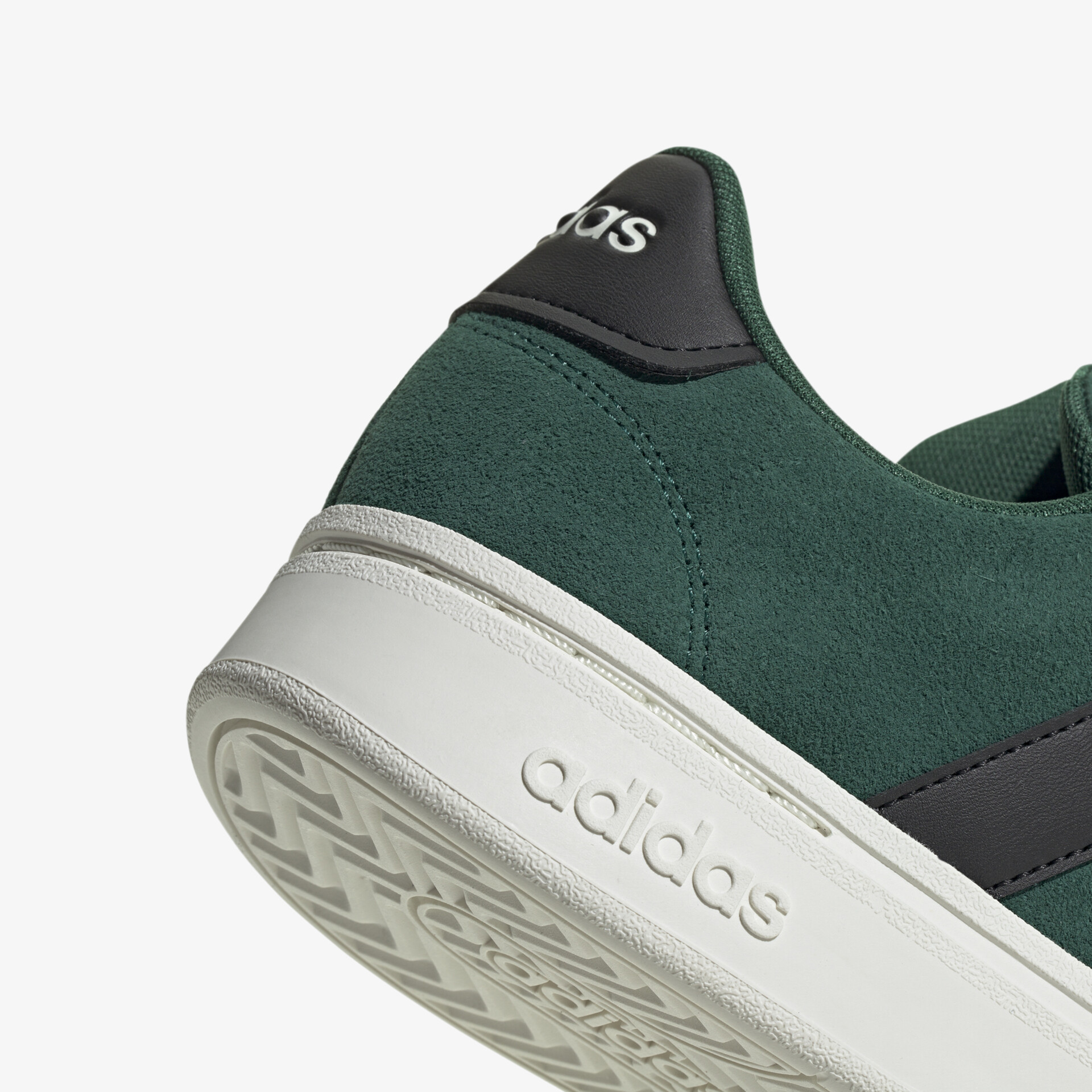 Nahaufnahme eines grünen Adidas Sportschuhs mit robuster weißer Sohle und markantem Detail am Fersenbereich