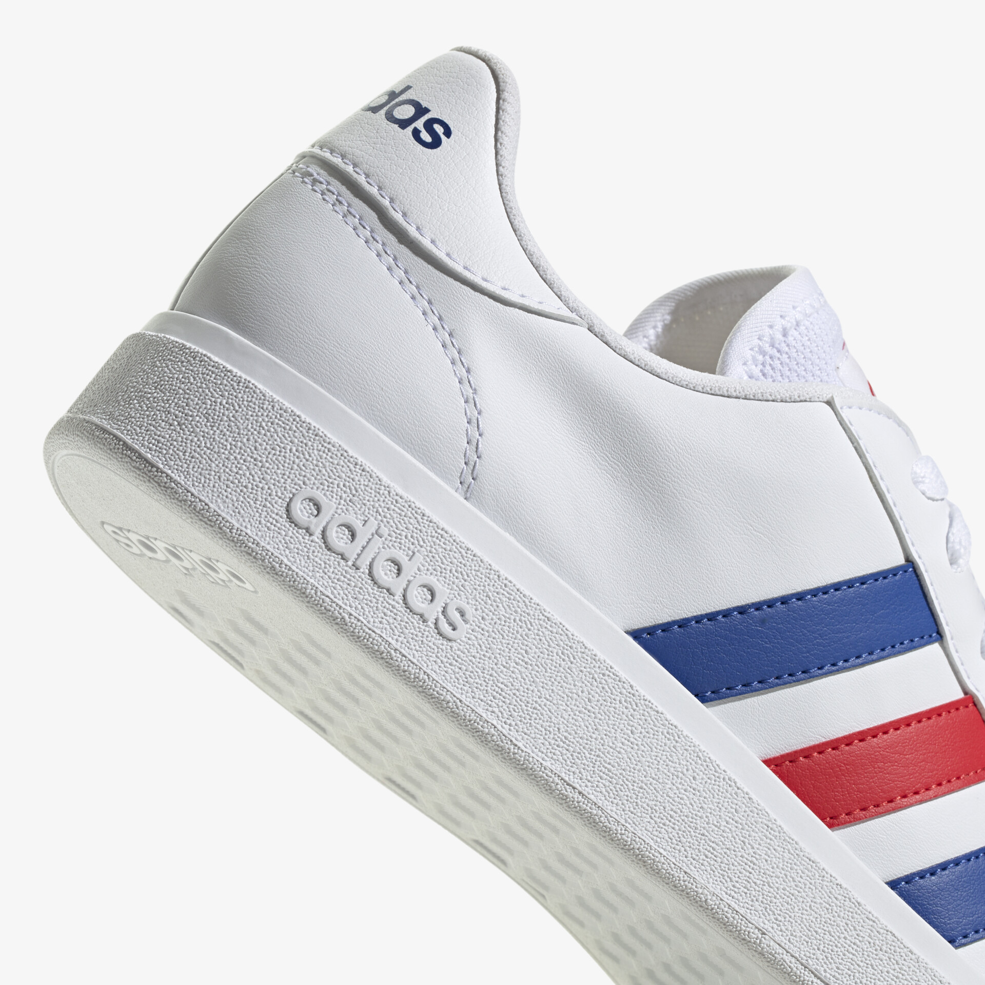 Moderner weißer Sneaker mit blauen und roten Streifen und robustem Sohlenprofil. Ideal für sportlichen Look.