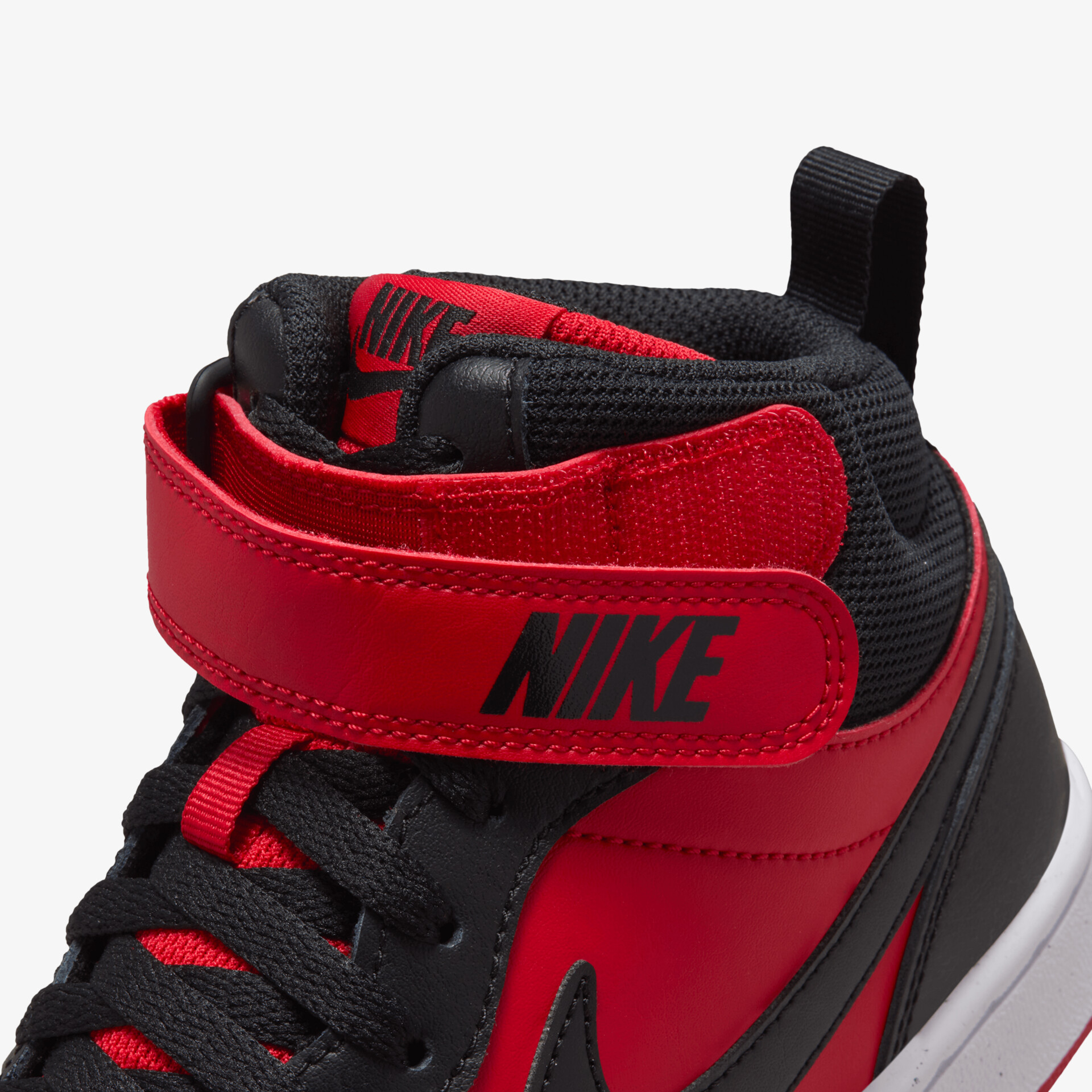 Nahe Aufnahme eines roten und schwarzen Nike-Sportschuhs mit Klettverschluss und Schnürsenkeln in Detailansicht