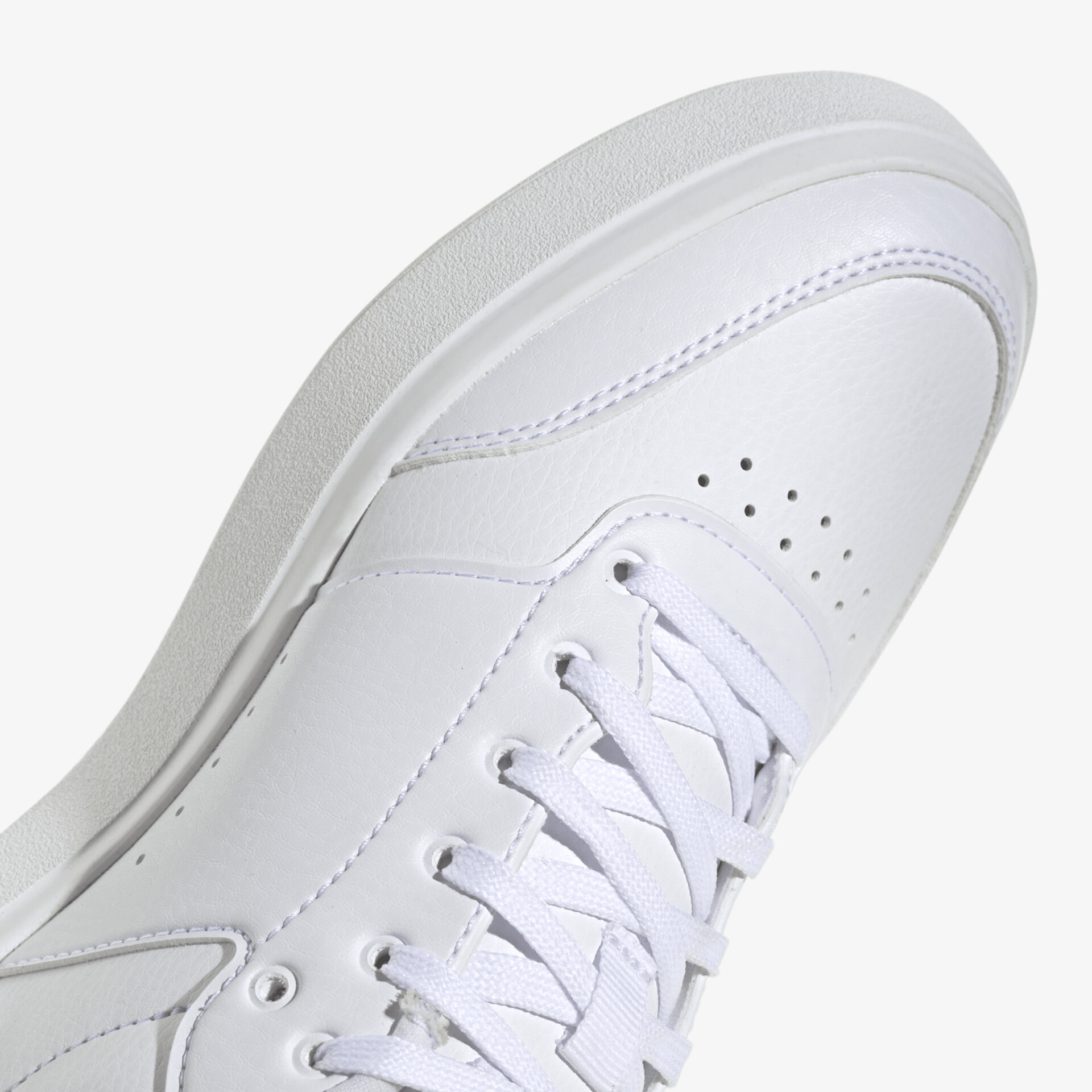 Detailaufnahme eines modernen weißen Sneakers mit perforiertem Design und Schnürsenkeln für optimalen Komfort