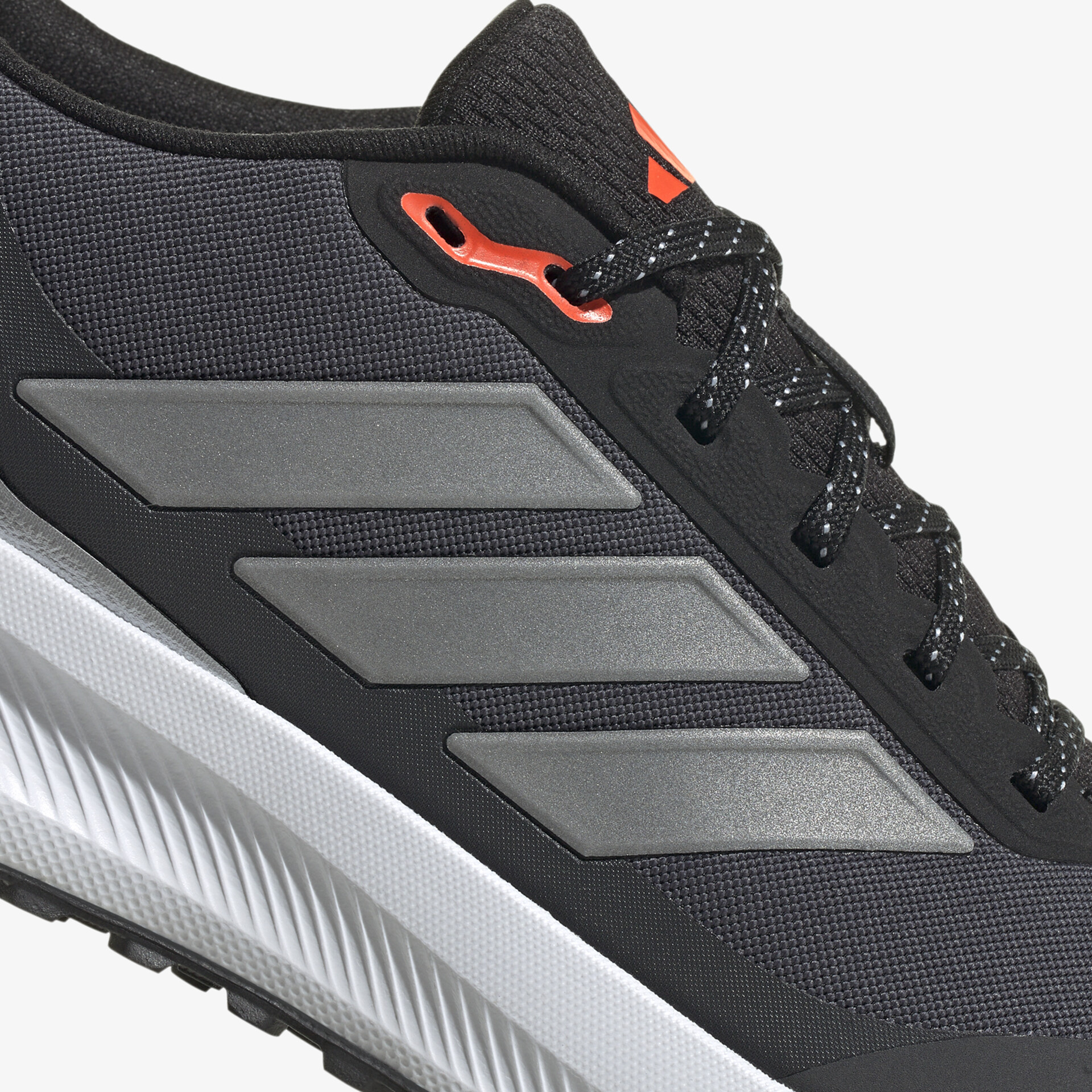 Detailaufnahme eines schwarzen Sportschuhs mit grauen Streifen und robusten Schnürsenkeln