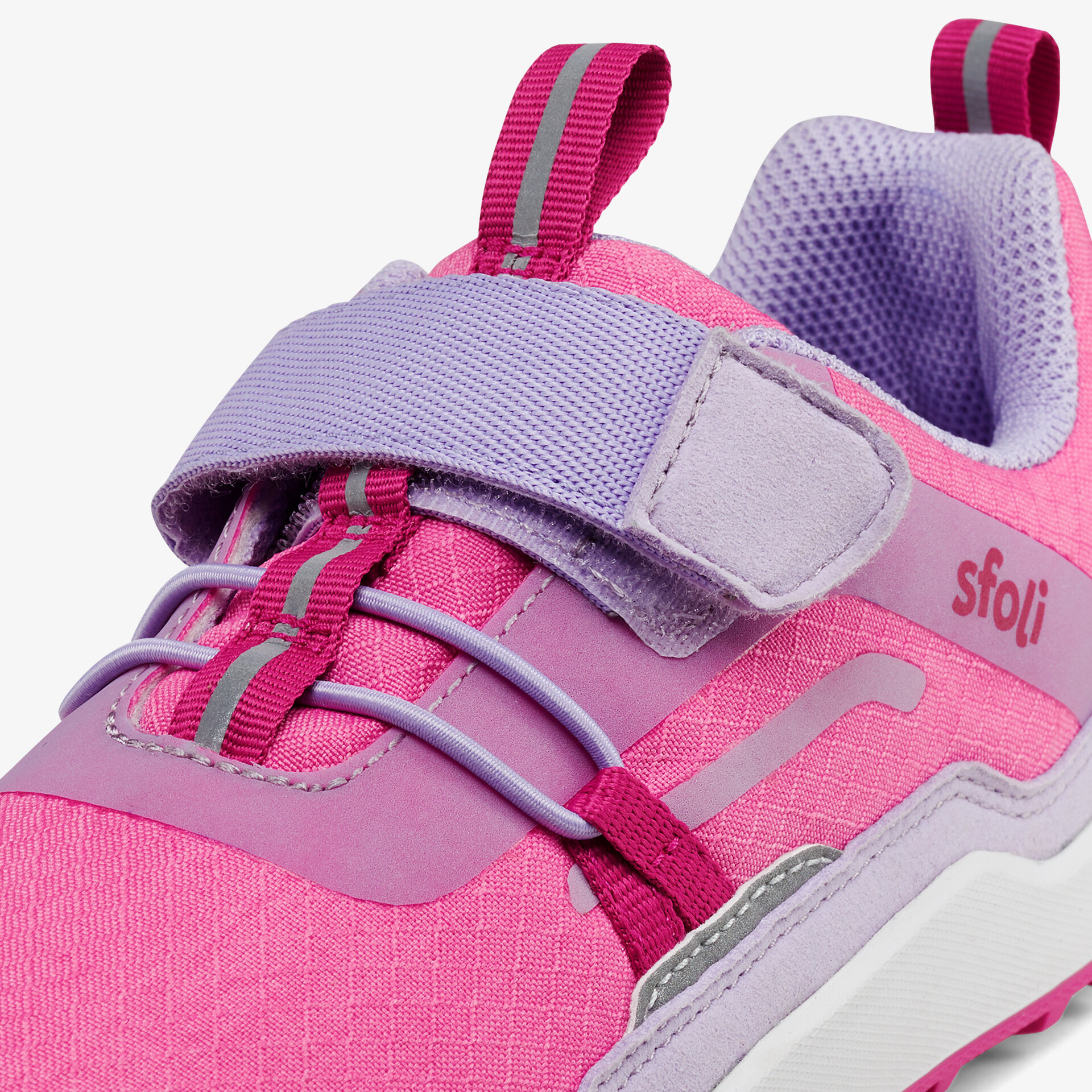 Detailaufnahme eines Sportschuhs mit verstellbarem Klettverschluss und atmungsaktivem Material in leuchtendem Pink