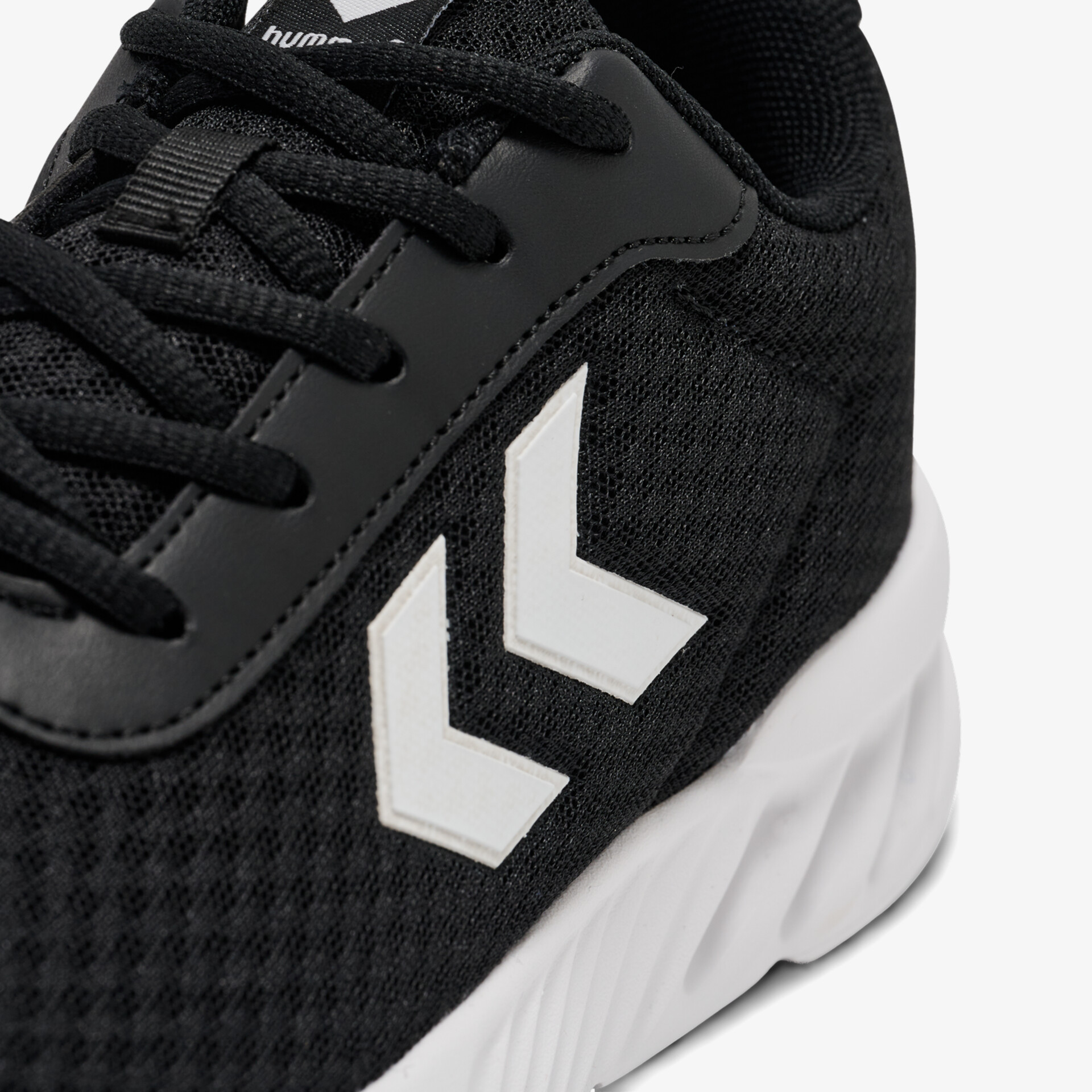 Nahaufnahme von schwarzem Sportschuh mit schnürung und weißem Pfeillogo auf seitlichem Mesh-Material