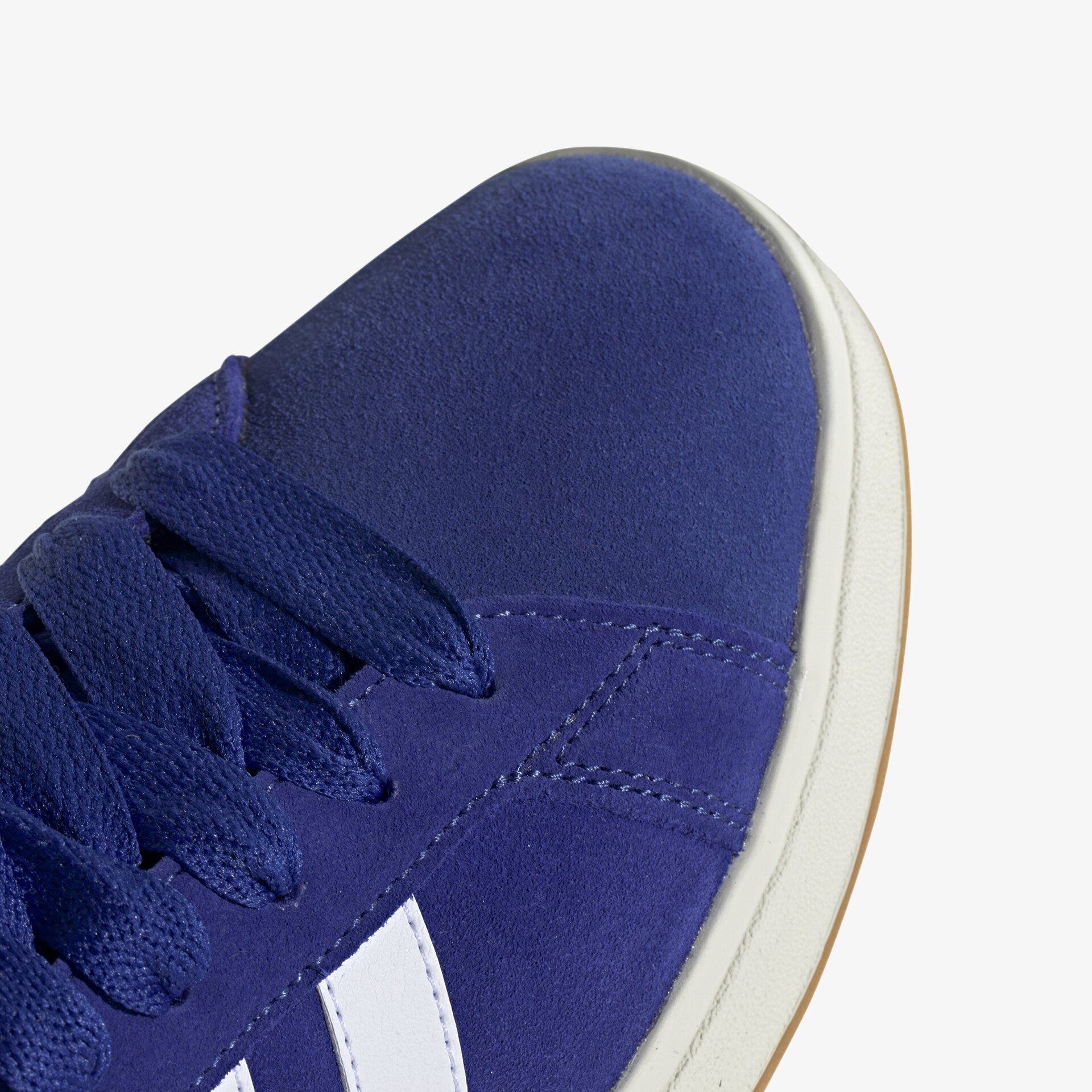 Detailaufnahme eines blauen Sneakers mit weißen Streifen und stabiler Schnürung, weiches Material sichtbar