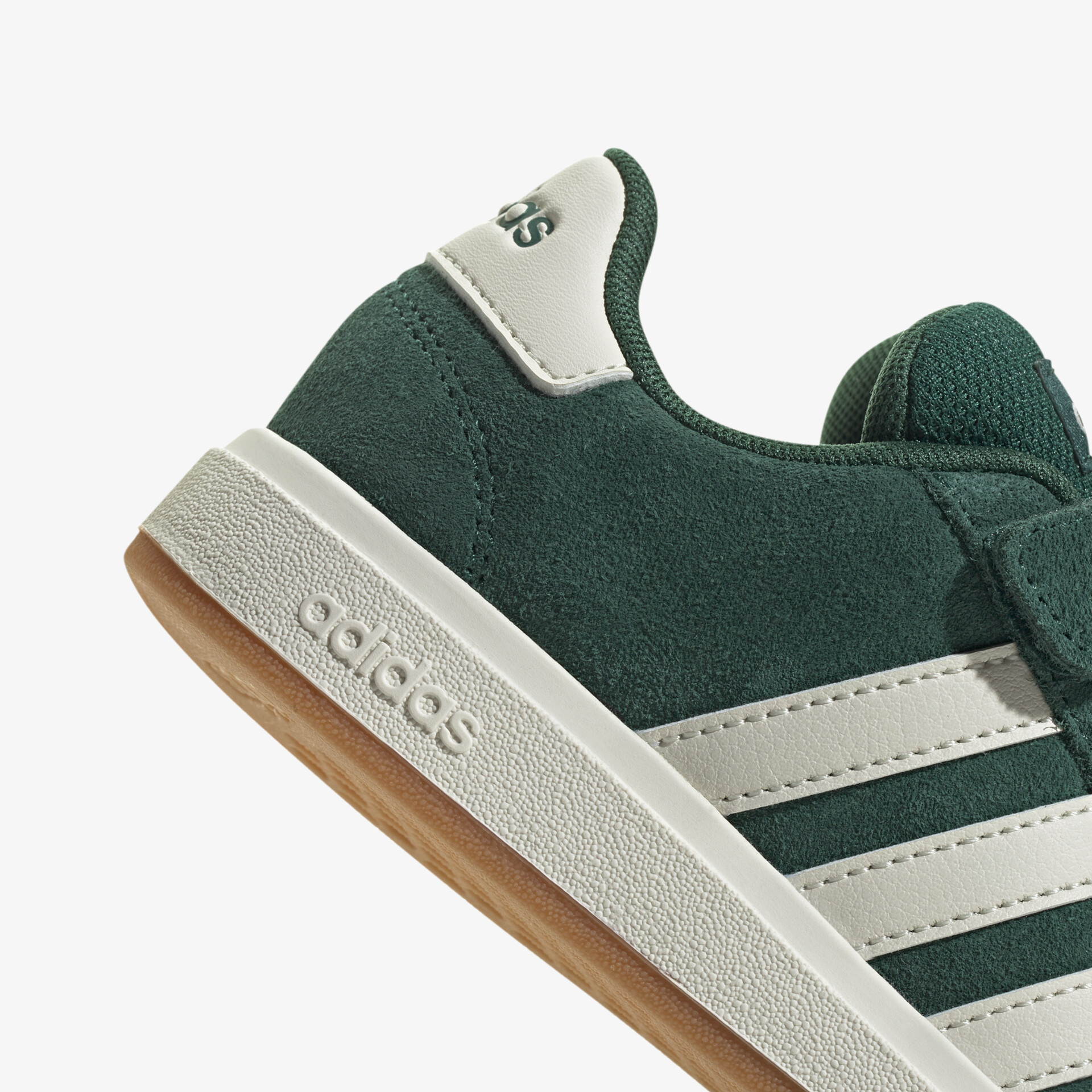 Nahaufnahme eines grünen Adidas Sneaker mit Wildleder-Material und weißer Sohle, modernes Design