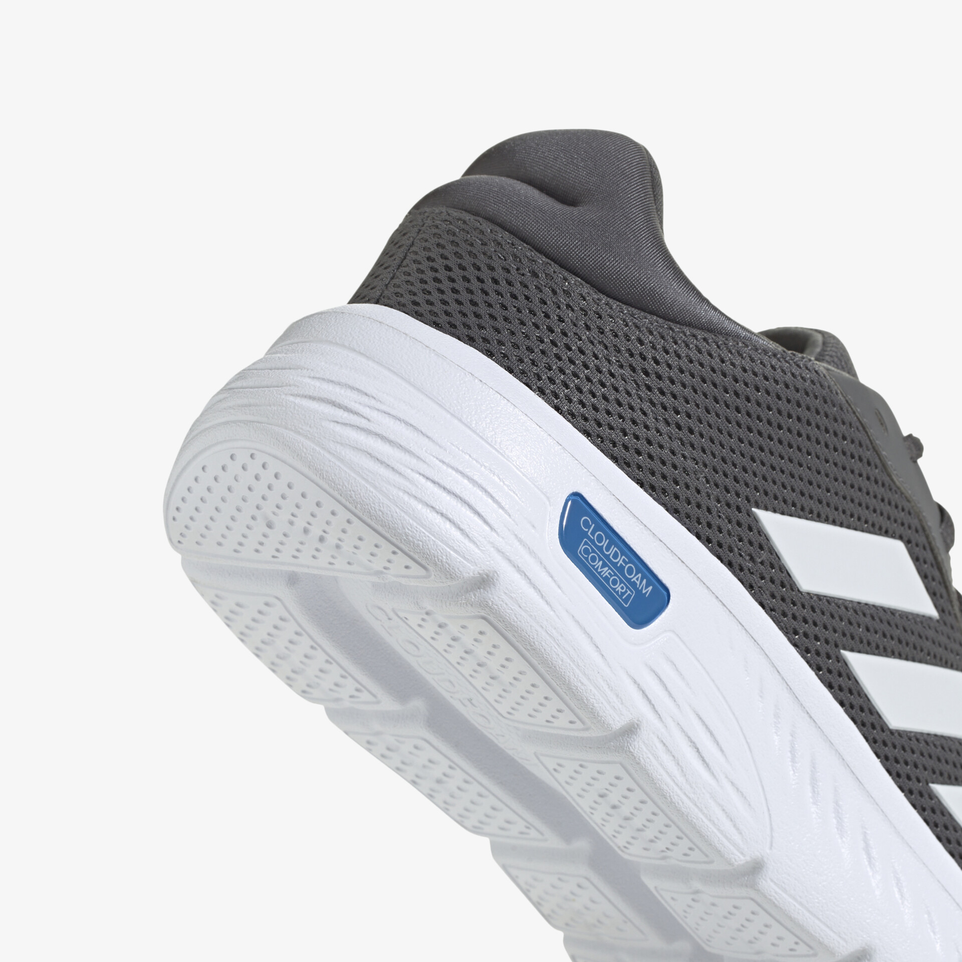 Detailaufnahme eines grauen Sneakers mit atmungsaktivem Mesh und gepolstertem Fersenbereich, weiße robuste Sohle