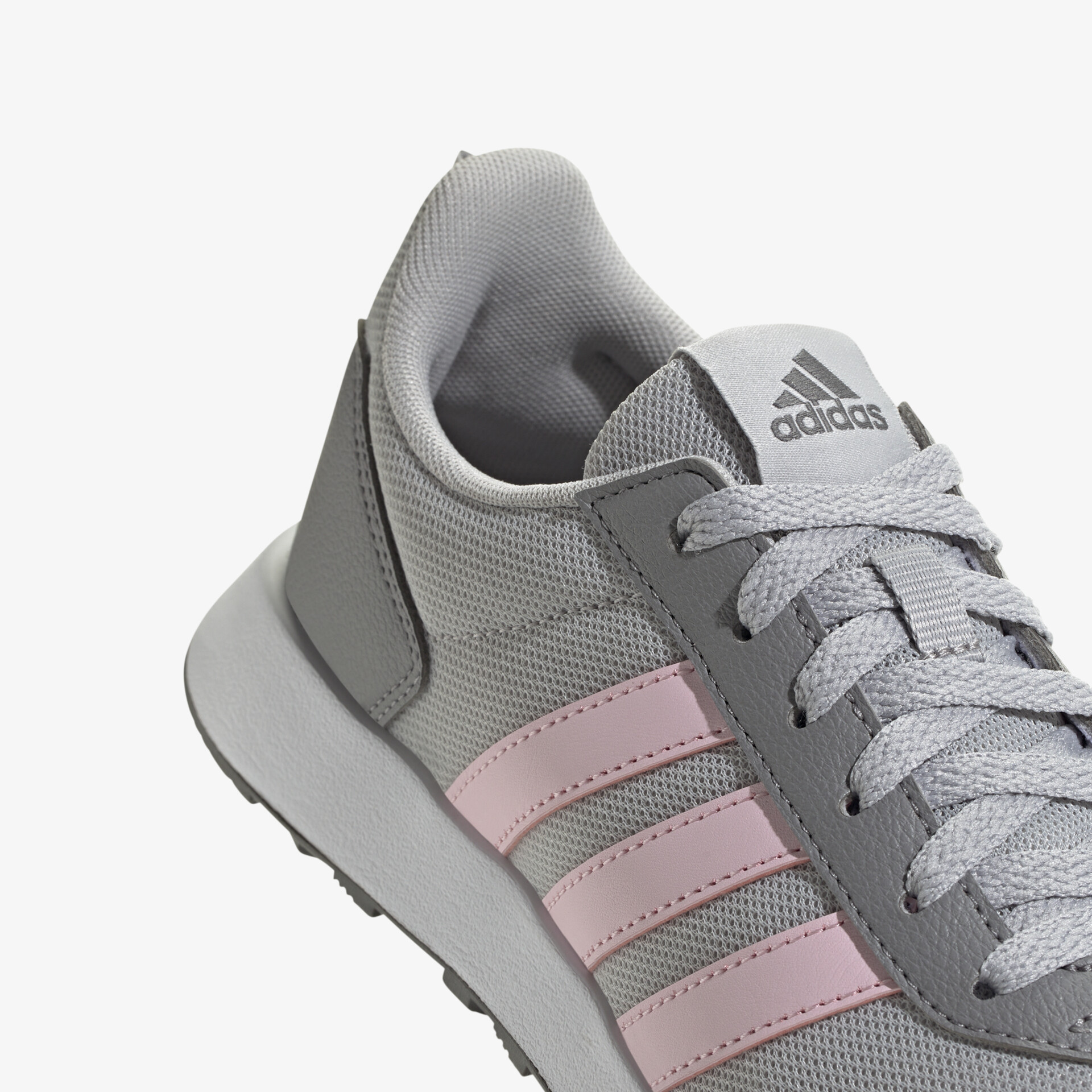 Detailaufnahme eines grauen Sneakers mit rosa Streifen, weiches Obermaterial und sportliche Schnürung sichtbar