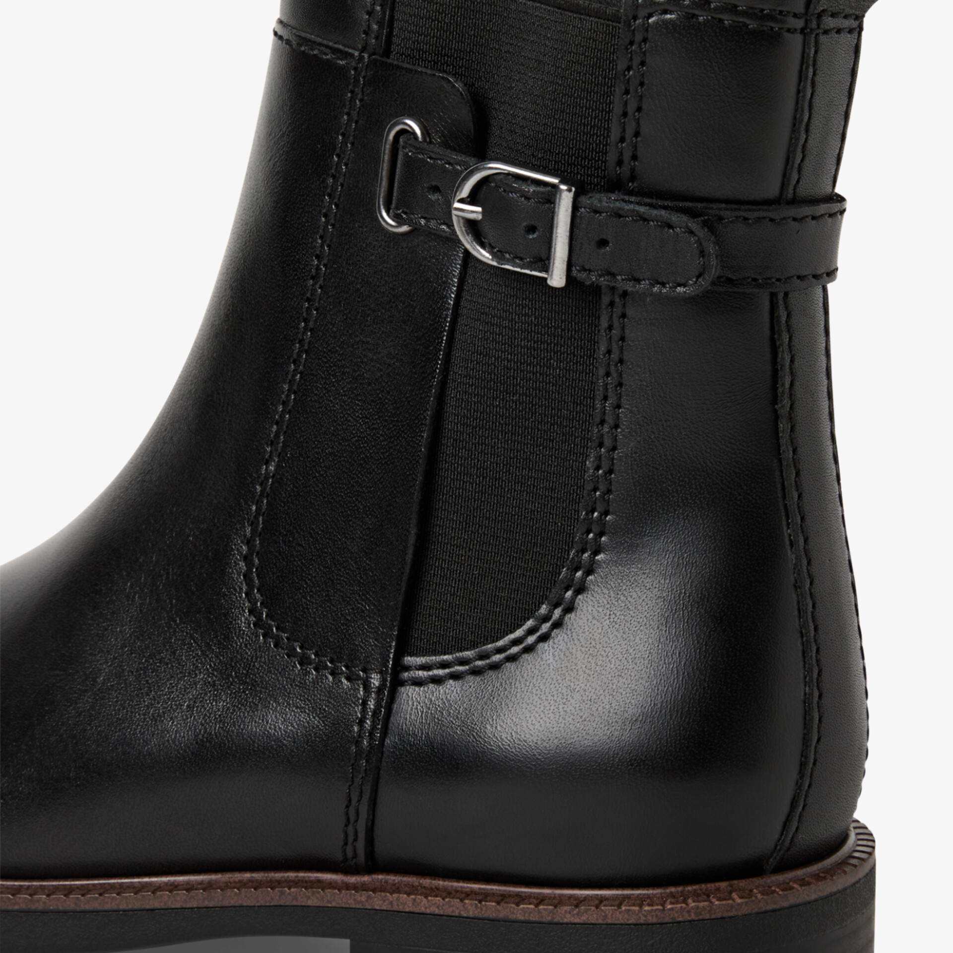 Schwarzer eleganter Stiefel aus Leder mit dekorativer Schnalle und robuster brauner Profilsohle