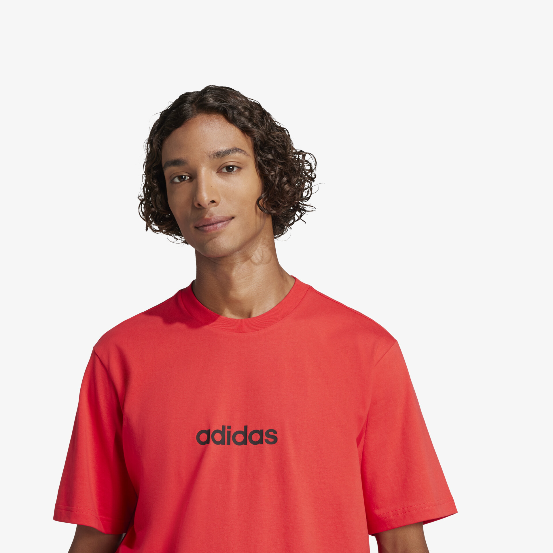 Modell trägt rotes Adidas Shirt mit kurzem Arm, schlicht und modern, ideal für sportliche und Freizeitaktivitäten