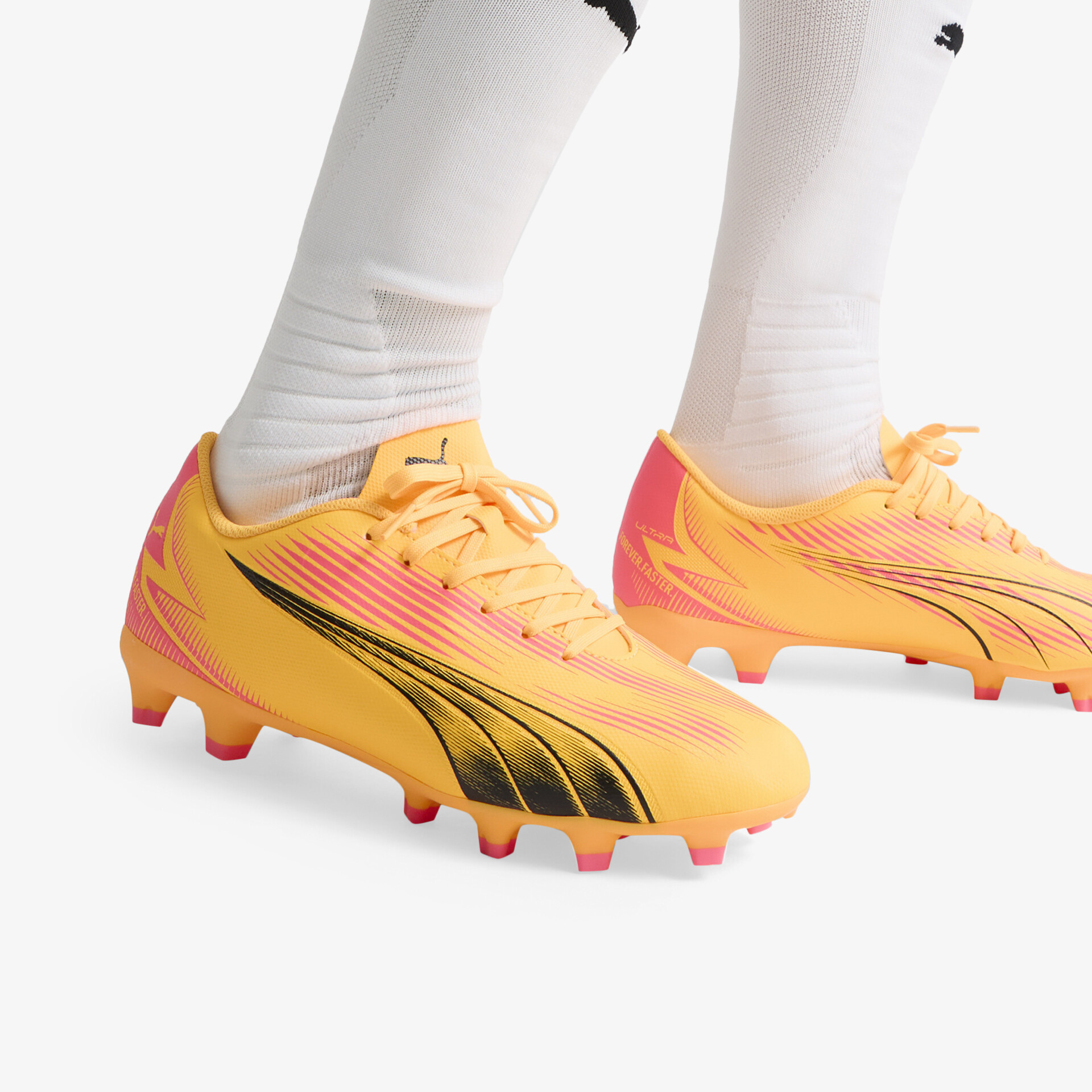 Gelb-orange Fußballschuhe mit schwarzem Logo, schnürbar, robuste griffige Sohle und komfortables Design getragen