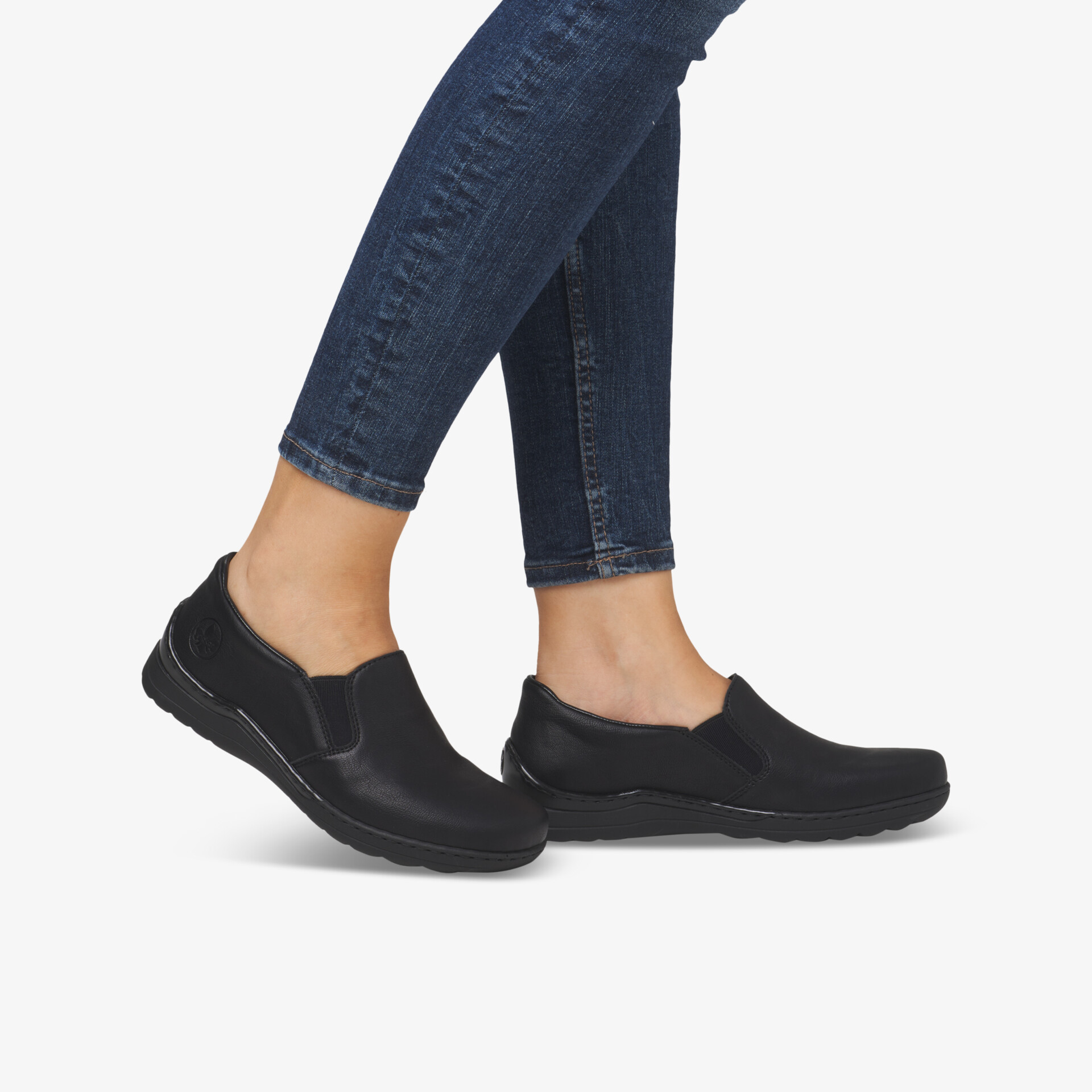 Bequeme schwarze Schuhe mit elastischem Einsatz und flexibler rutschfester Sohle seitlich am Fuß getragen