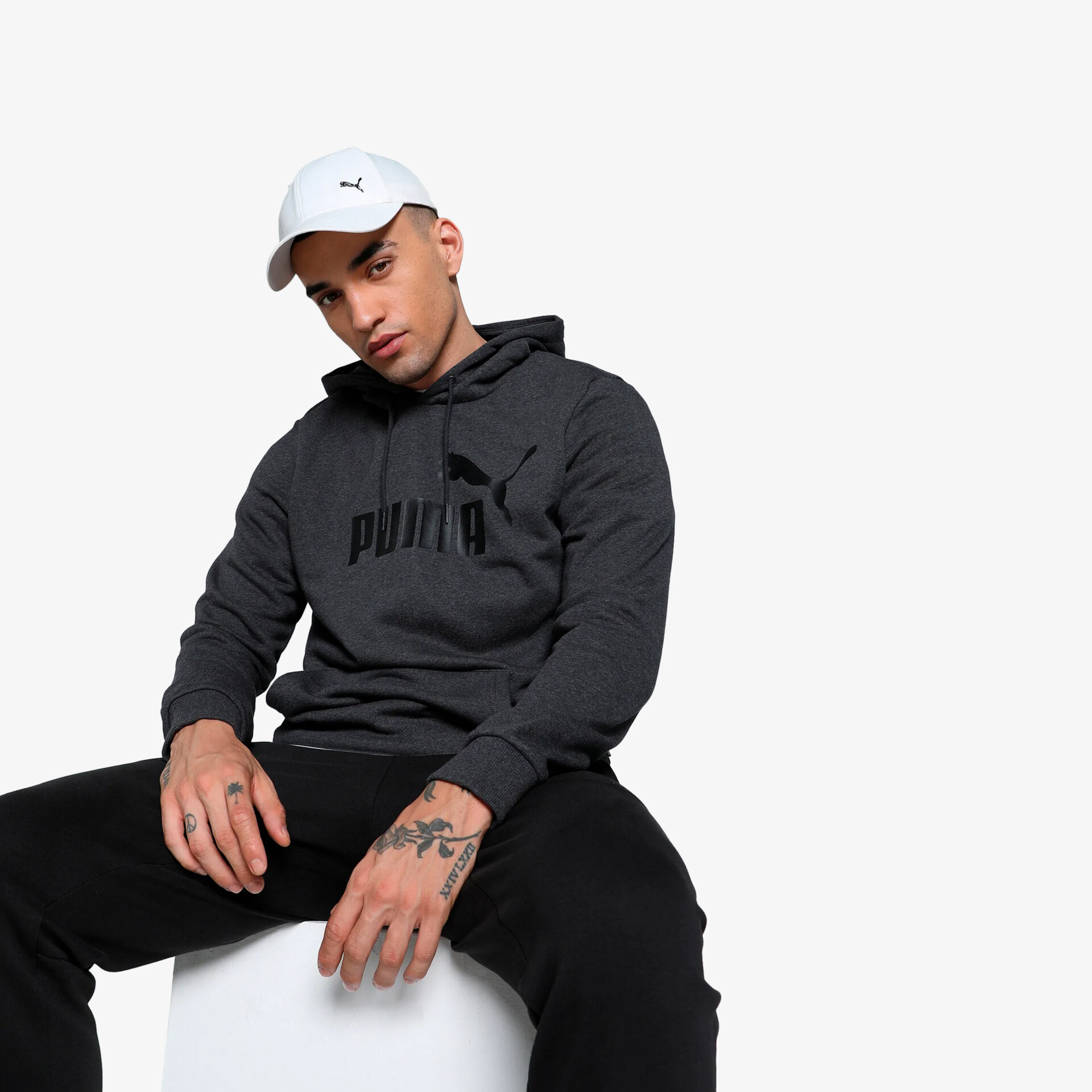 Modell trägt schwarzen Puma Kapuzenpullover mit dezentem Logo in sportlich lässiger Pose, bequem und modisch